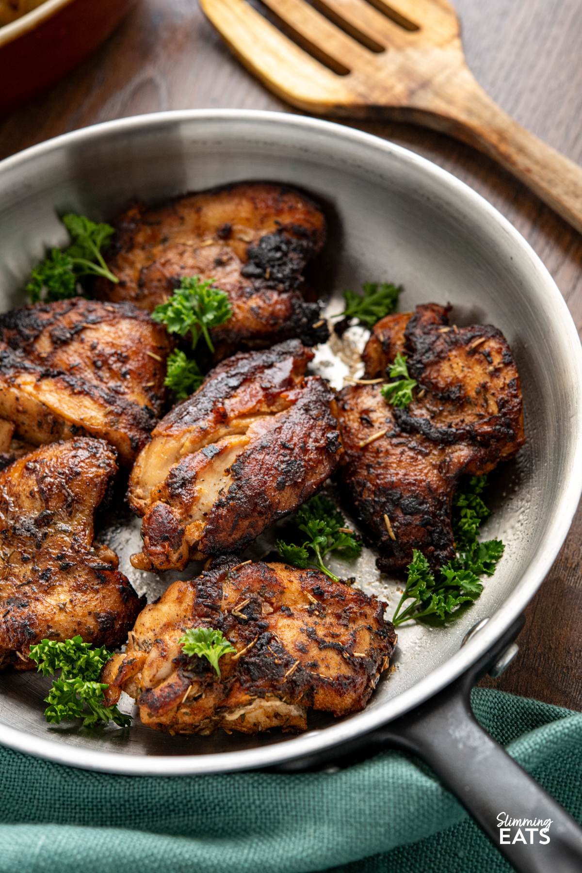 Seasoned Chicken with Rich Gravy - deliciously tender chicken thighs with seasoning and herbs paired with a delicious rich gravy. #glutenfree #dairyfree #chicken #gravy #slimmingeats #weightwatchers #smartpoints Seasoned Chicken in frying pan garnished with parsley, wooden spatula to the top right