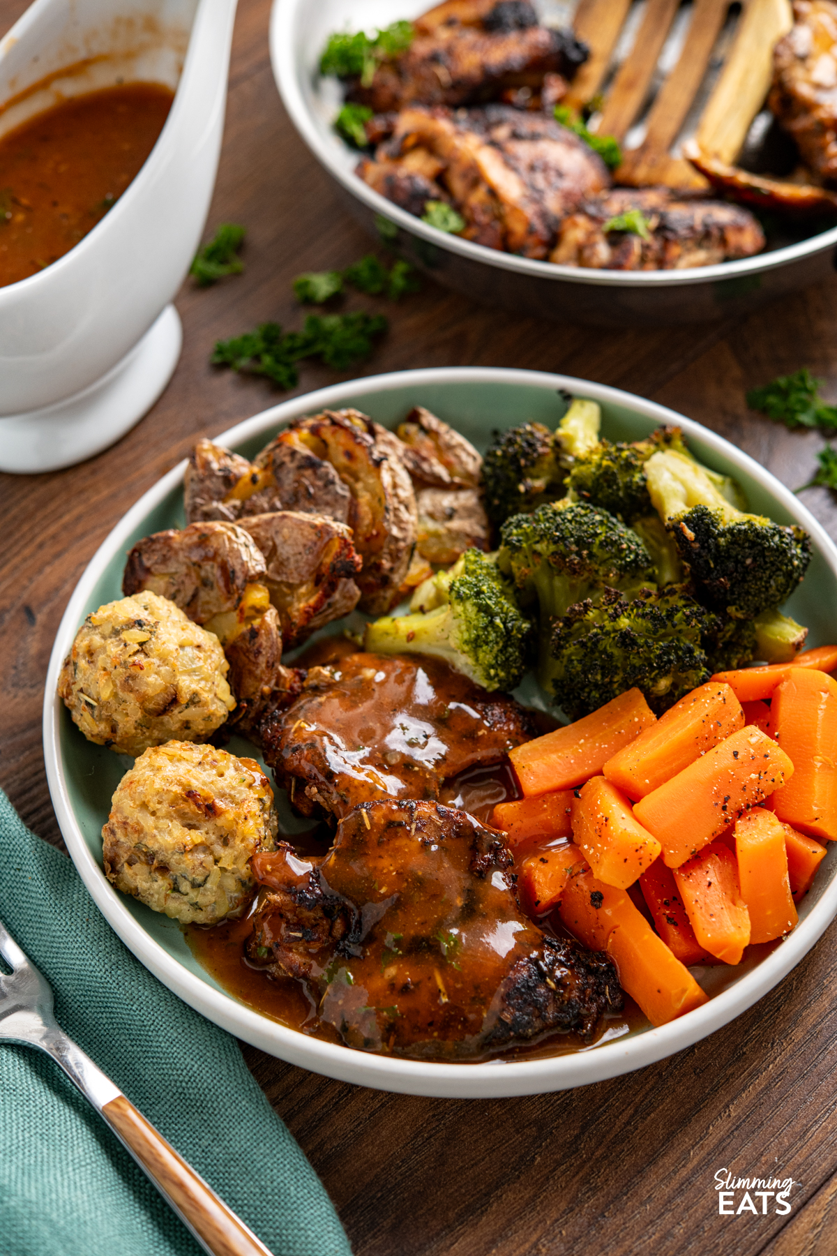 Seasoned Chicken with Rich Gravy - deliciously tender chicken thighs with seasoning and herbs paired with a delicious rich gravy. #glutenfree #dairyfree #chicken #gravy #slimmingeats #weightwatchers #smartpoints Seasoned Chicken with Rich Gravy on teal plate with stuffing balls, crushed potatoes, broccoli and carrots, jug of gravy in background.