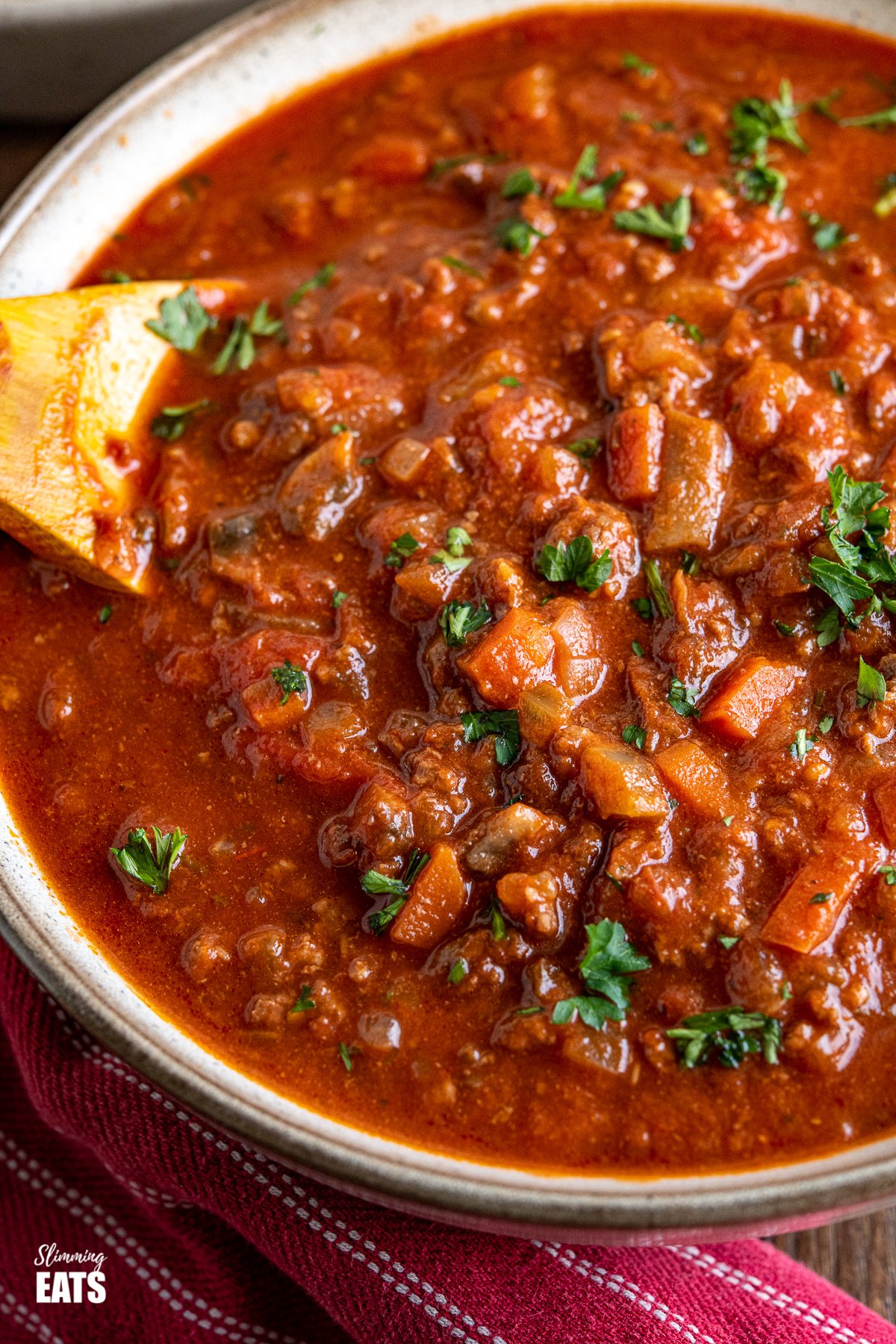 close up of Slow Cooker Bolognese Sauce in bowl with wooden spoon