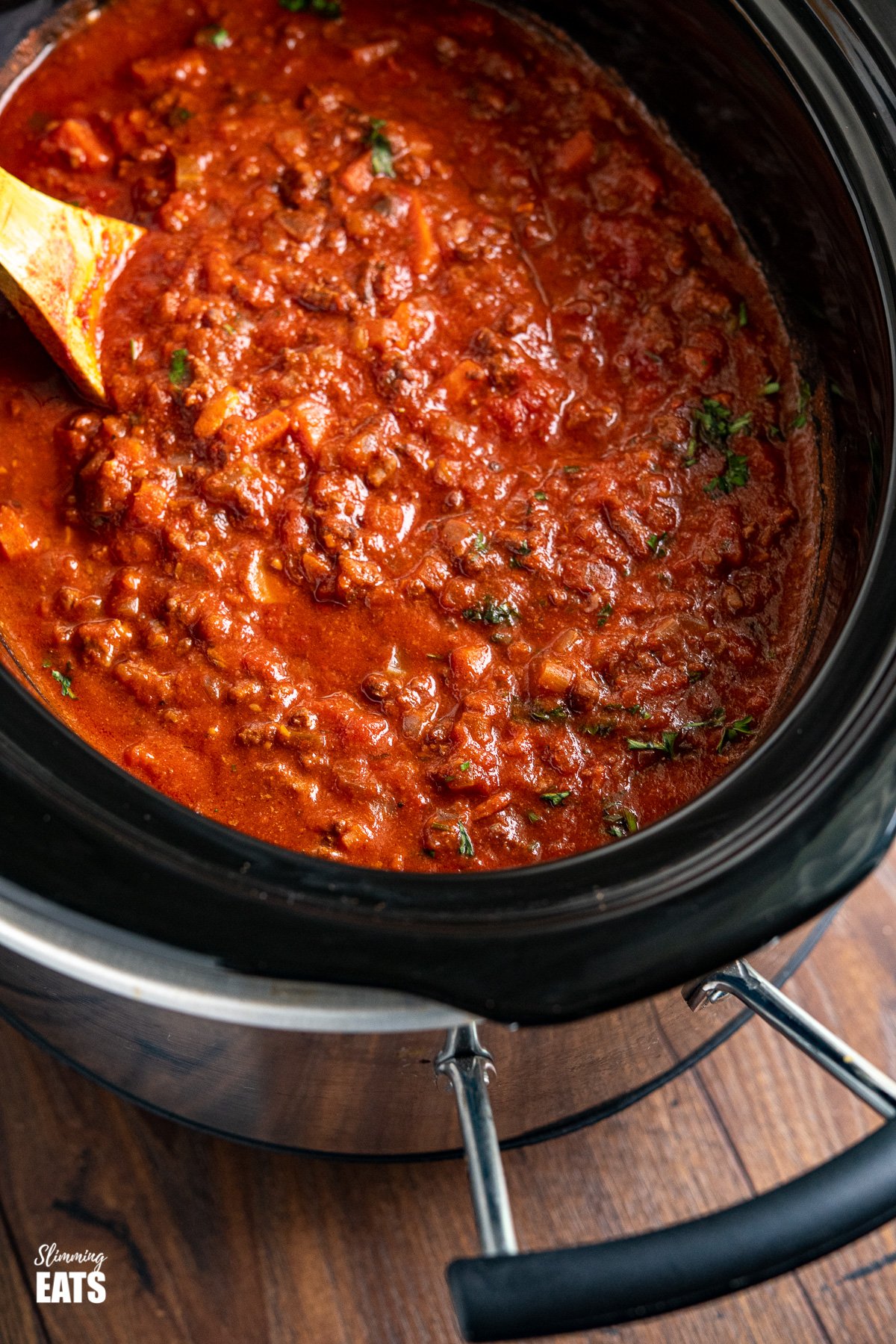 close up of Slow Cooker Bolognese Sauce in slow cooker with wooden spoon