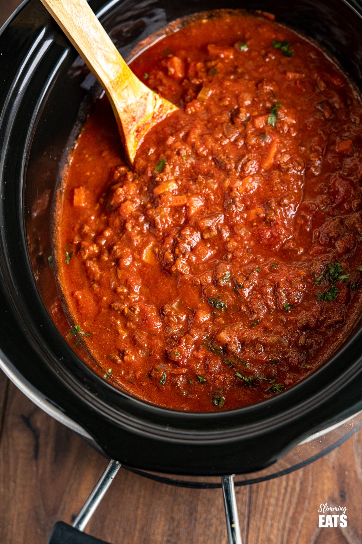 Slow Cooker Bolognese Sauce in slow cooker with wooden spoon