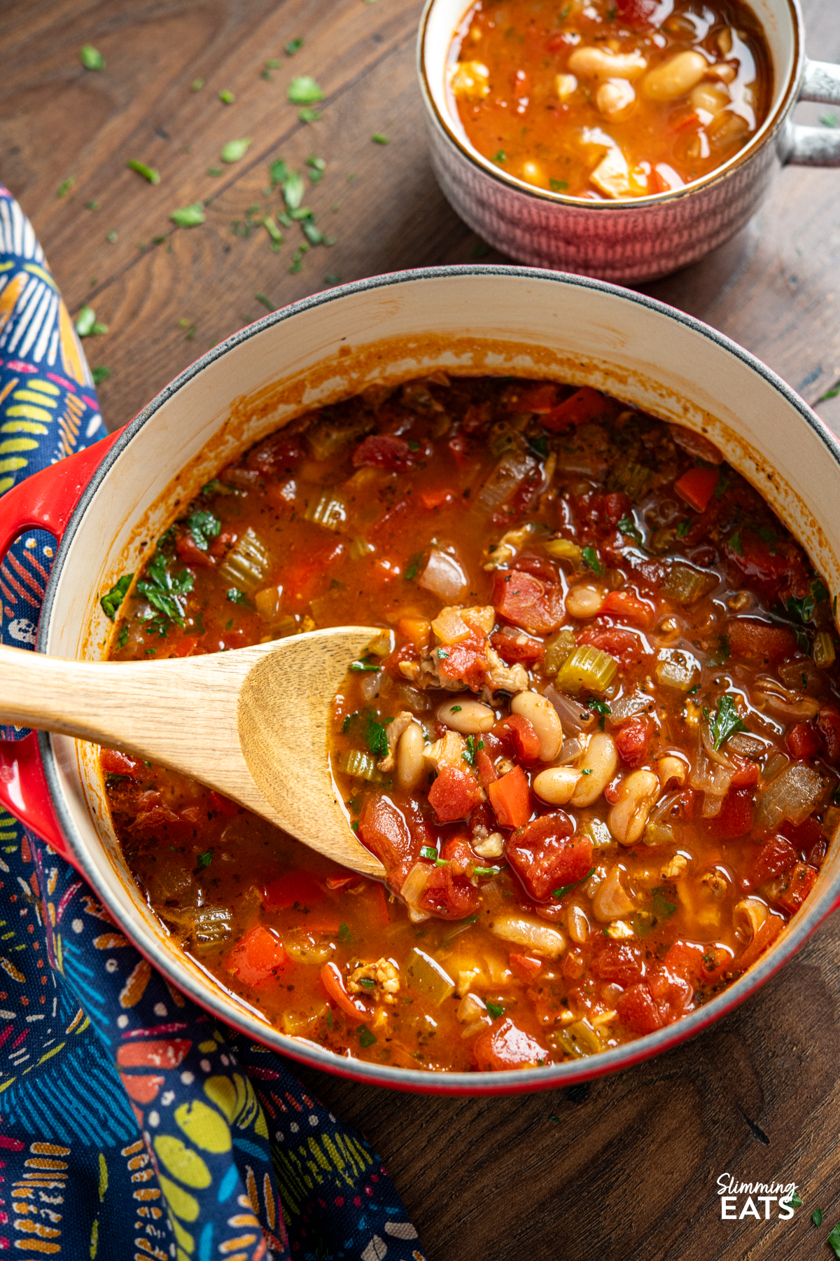 Chicken, Tomato and White Bean Soup - this hearty flavoursome soup is a complete meal in a bowl that the whole family will love. chicken, tomato and white bean soup in a cerise cast iron pot with mug of soup in background