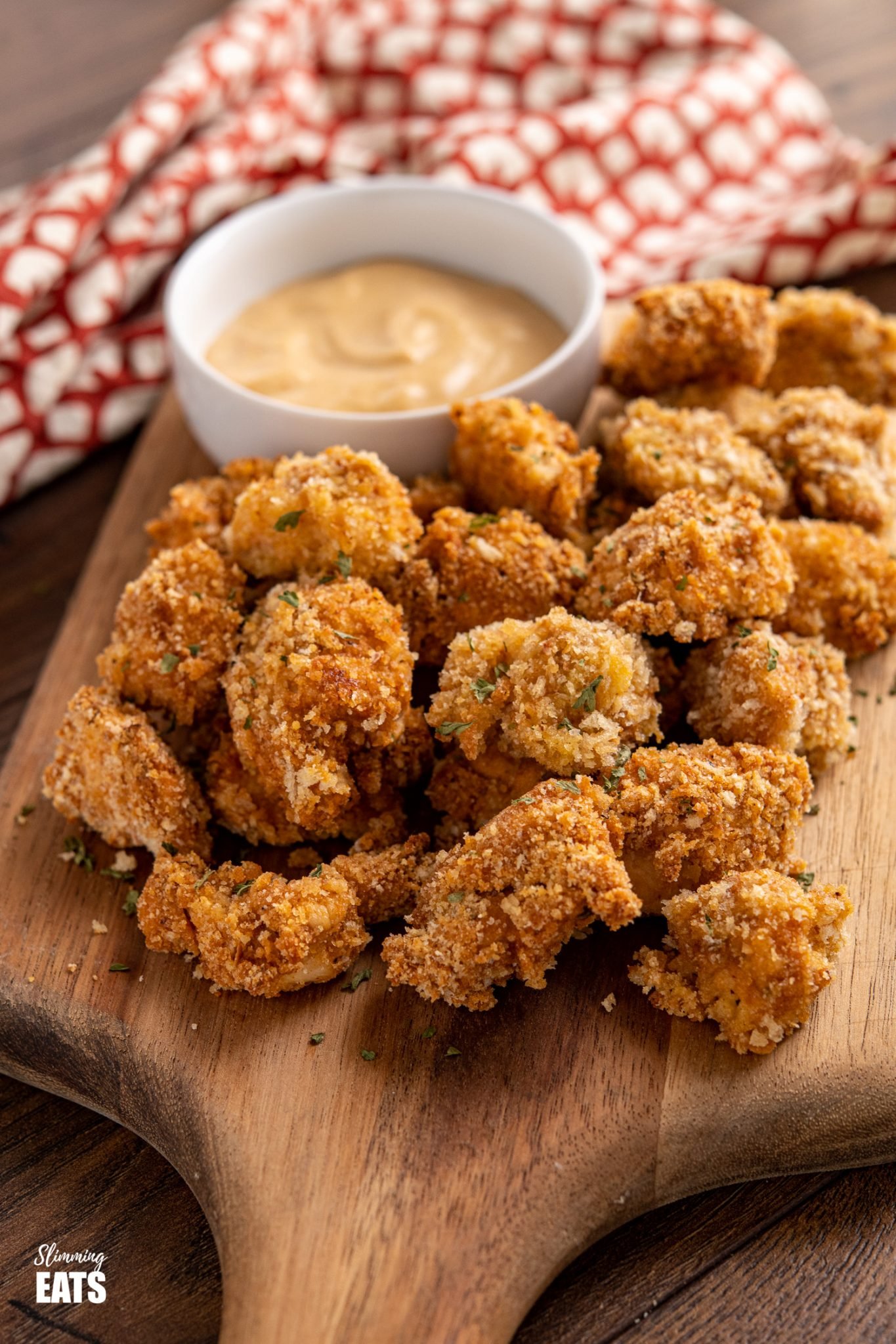 oven baked popcorn chicken bites on a wooden board with chicken dipping sauce