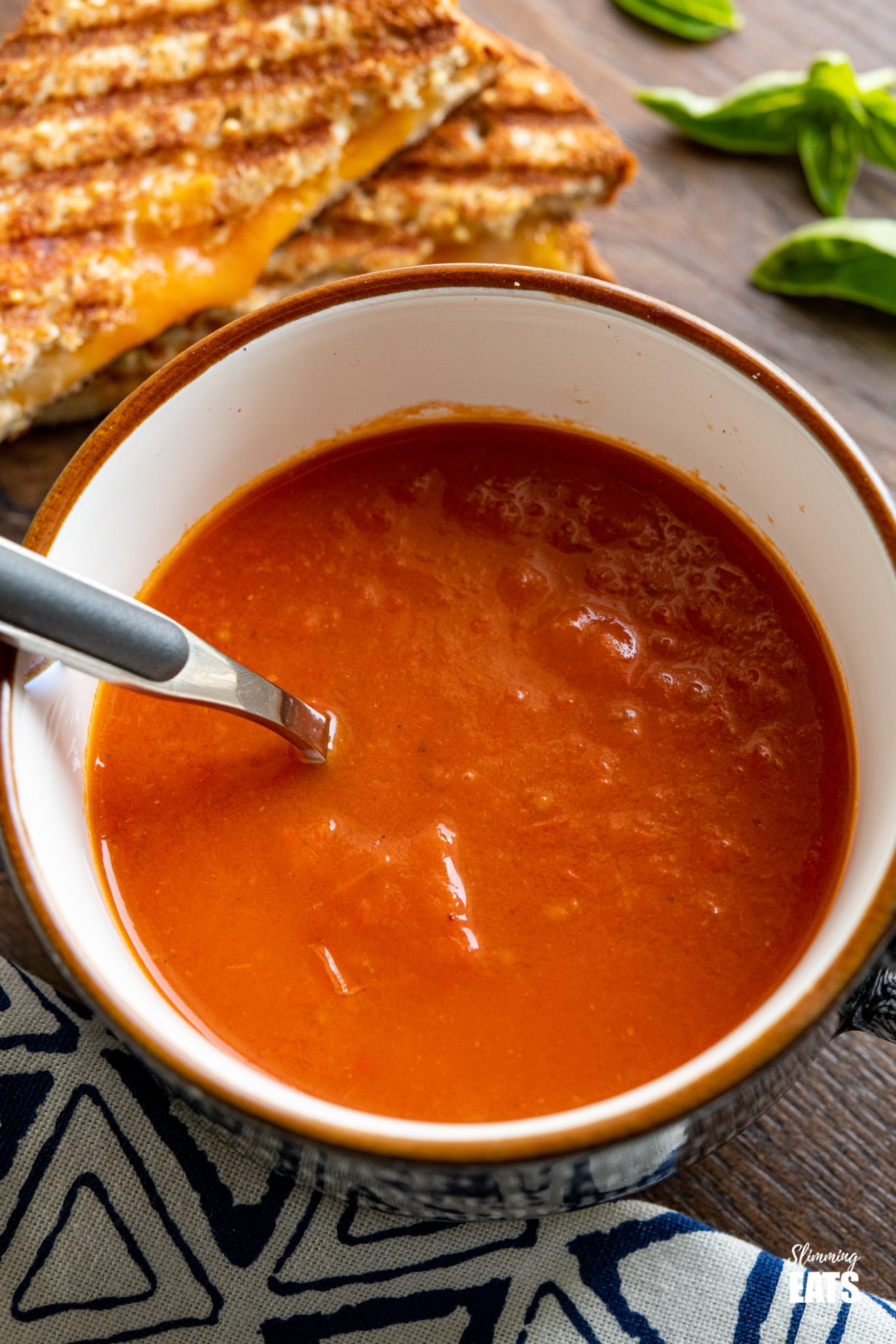 close up of cup of Roasted Red Pepper and Tomato Soup with spoon