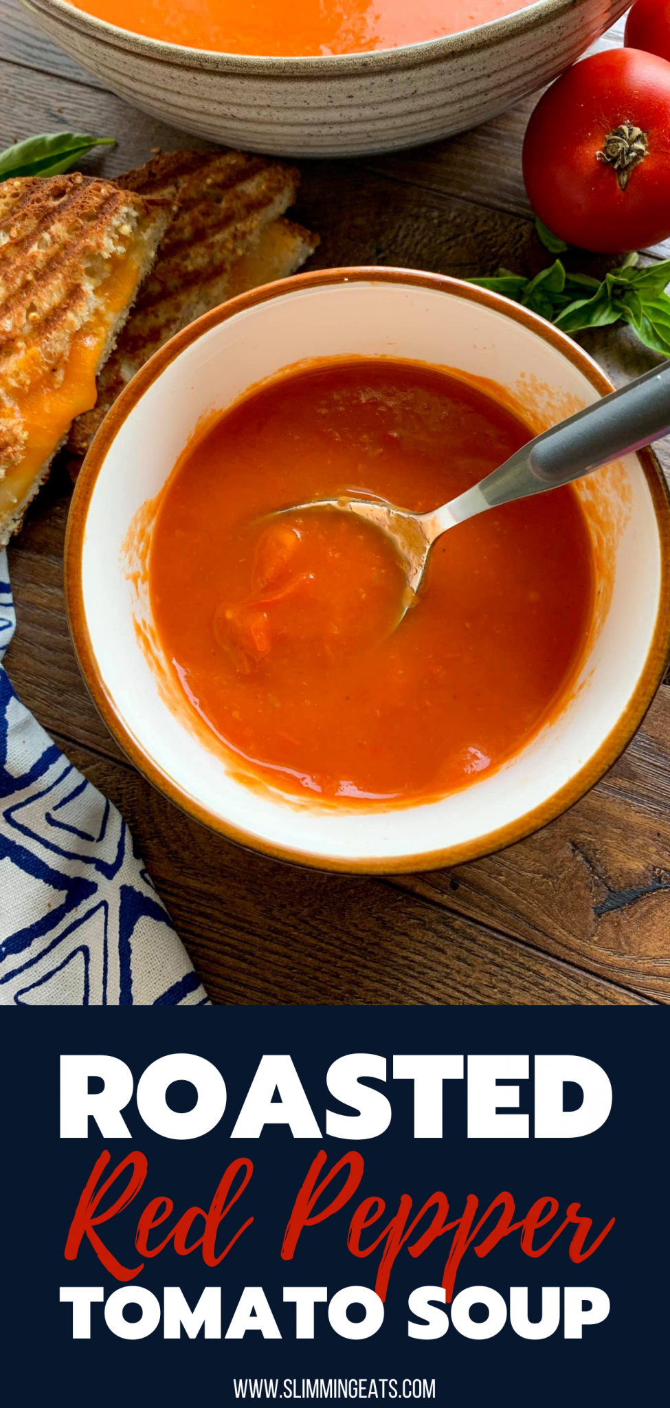 Roasted Red Pepper and Tomato Soup in cup with spoon, grilled. cheese to left and scattered tomatoes and basil to right.