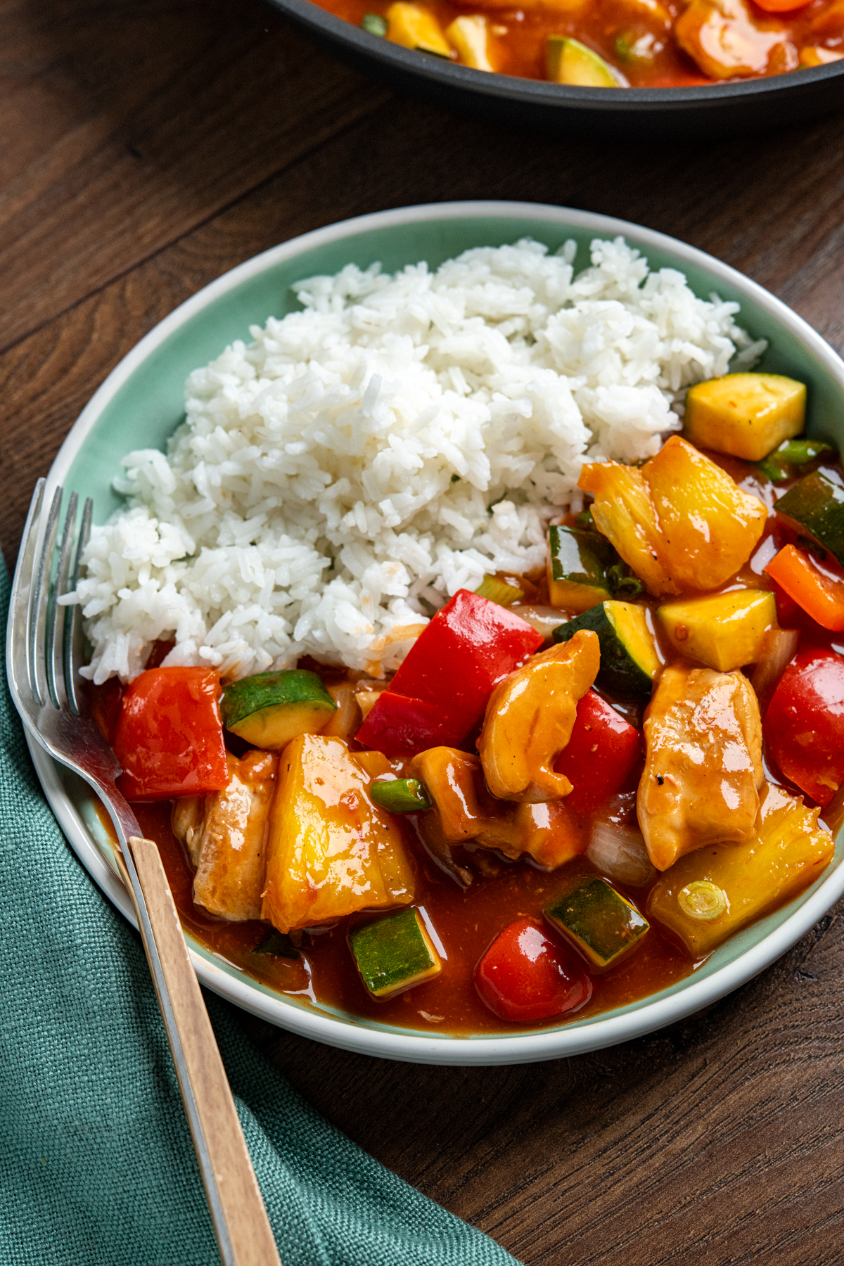 Sweet and Sour Chicken - a classic Chinese recipe you can make in your own home, with tender pieces of chicken thigh, fresh vegetables and pineapple in a delicious sauce. Dairy Free, Gluten Free, Slimming Eats and Weight Watchers friendly close up of chinese sweet and sour chicken in teal bowl with rice