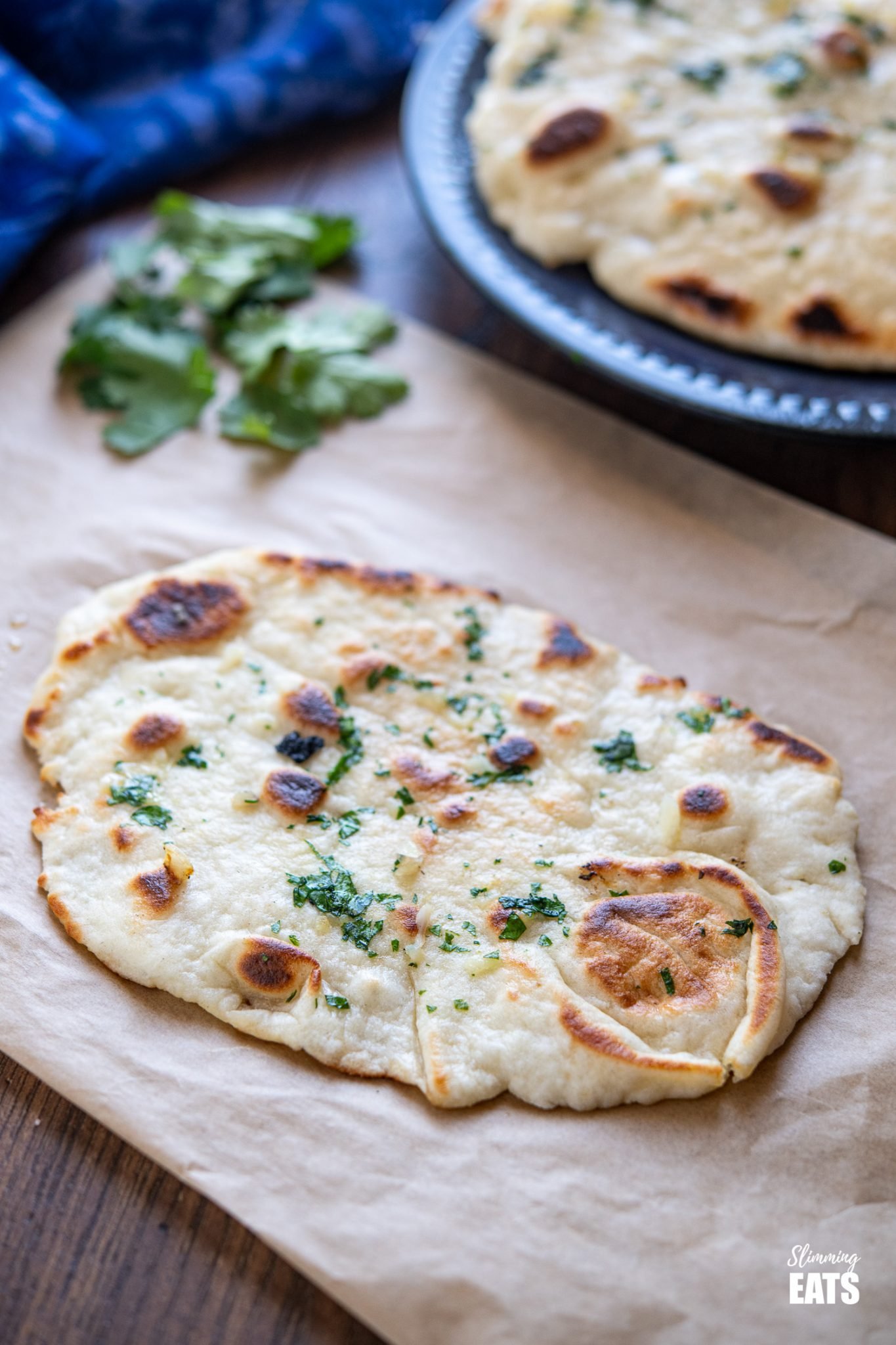 Garlic Greek Yoghurt Naan Bread on a sheet or parchment paper with scattered cilantro