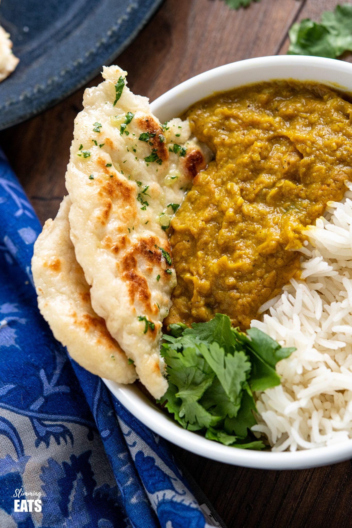 close up of Garlic Greek Yoghurt Naan Bread in white bowl with dhal and rice