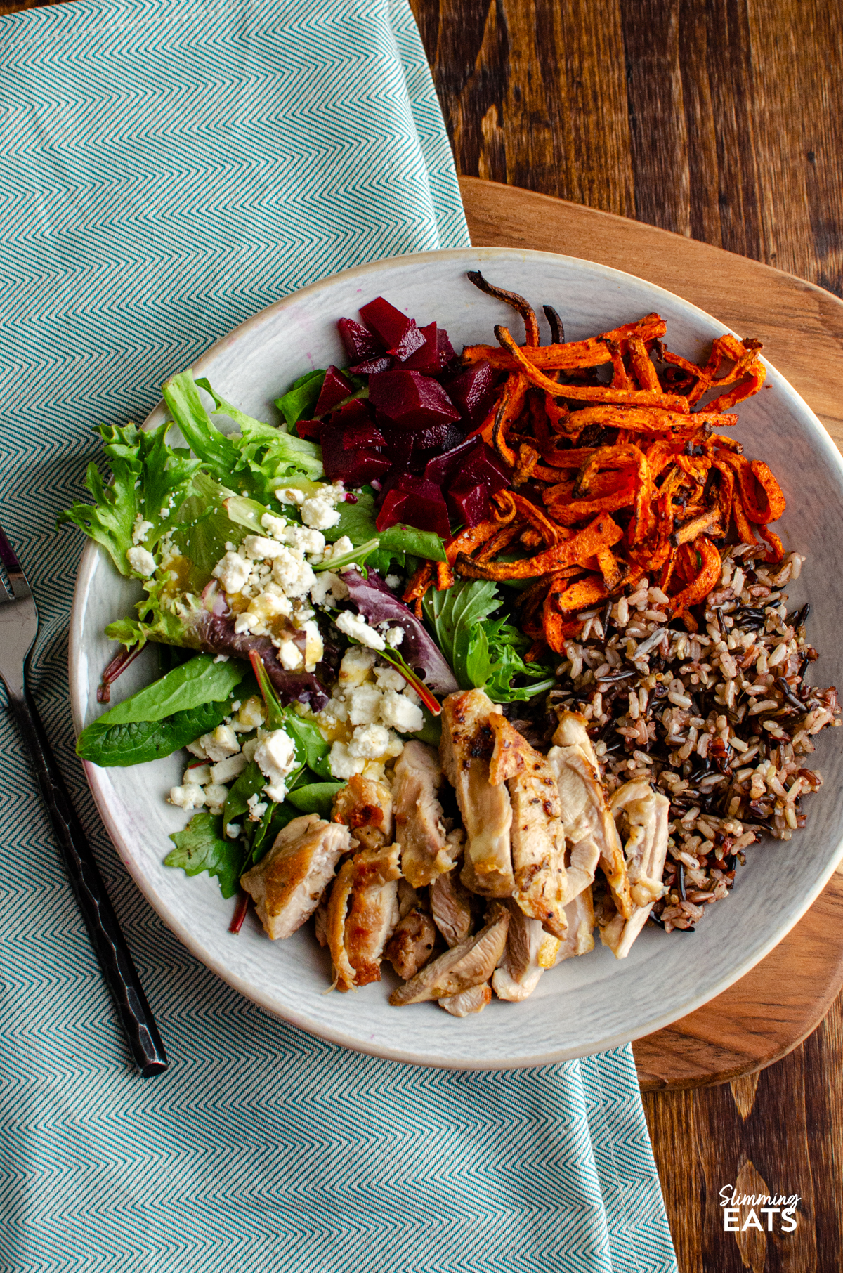 Chicken Wild Rice Bowl - tender seasoned chicken thighs with a delicious nutty wild rice blend, roasted carrot strands, salad with beets and feta in a bowl with fork