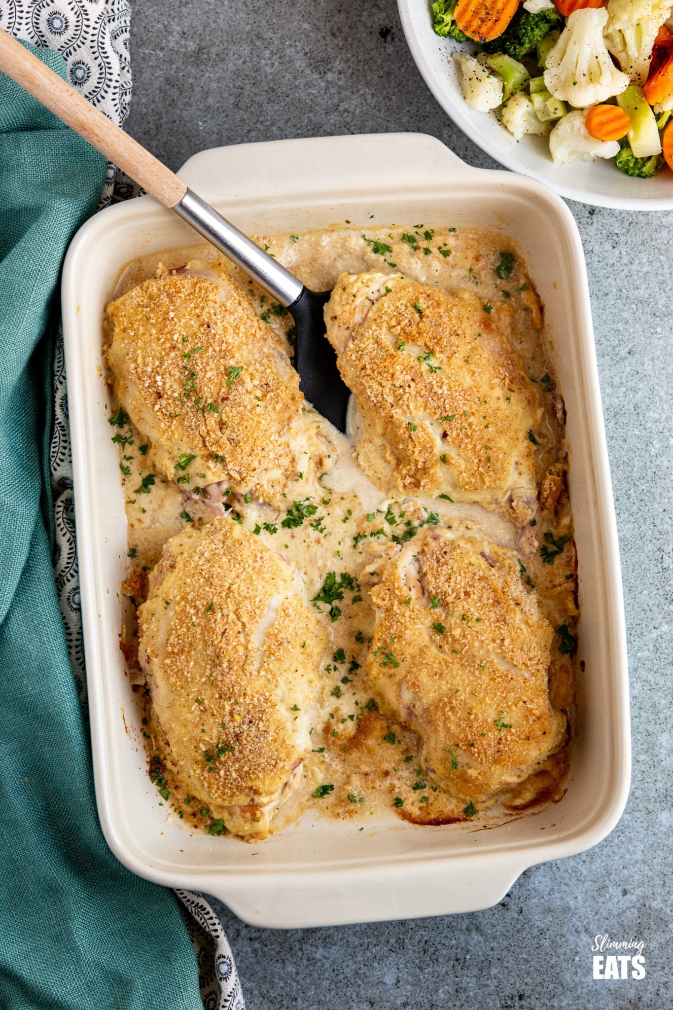 Easy Chicken Cordon Bleu  in baking dish with bowl of steam veg above