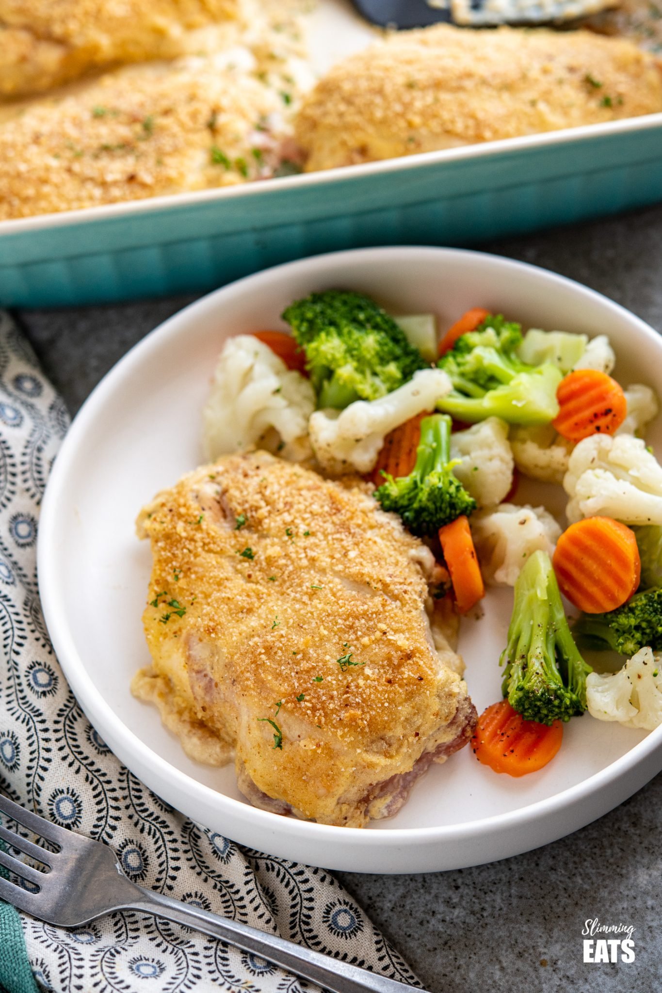 Easy Chicken Cordon Bleu - tender chicken breasts, topped with ham, swiss cheese, healthier dijon creamy sauce and breadcrumbs. Slimming World and Weight Watchers friendly Easy Chicken Cordon Bleu on white plate with steamed vegetables