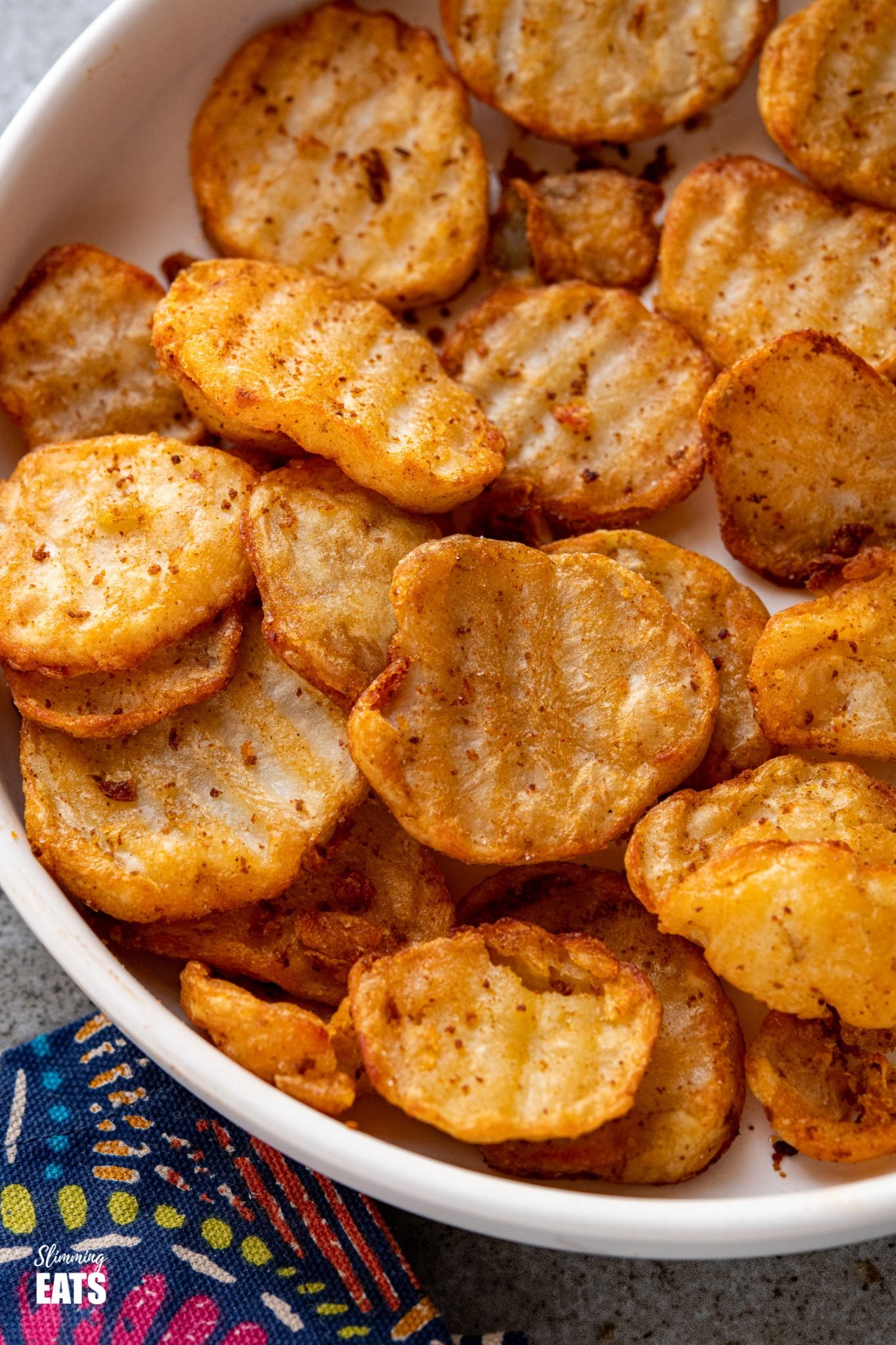 close up of crispy potato slices in white bowl