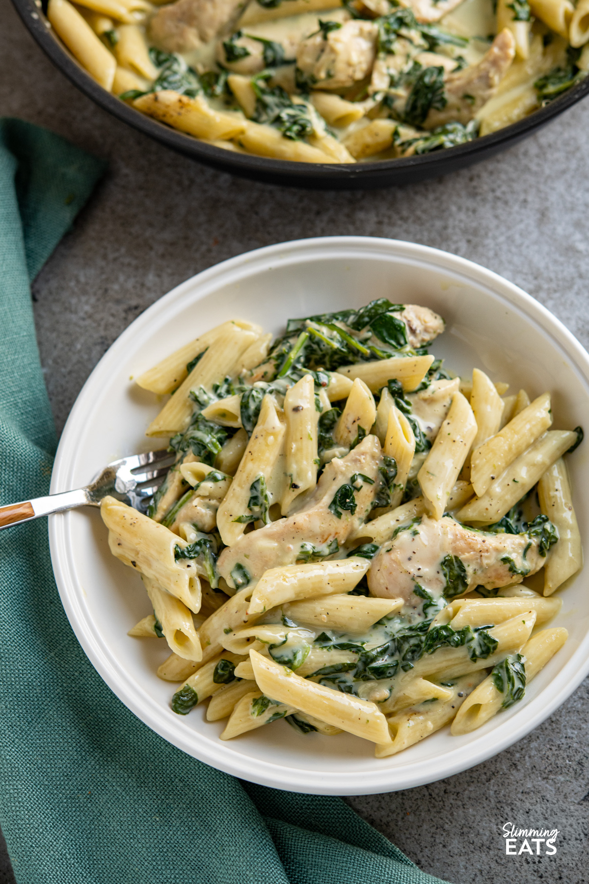 creamy garlic chicken with spinach and penne pasta in white bowl