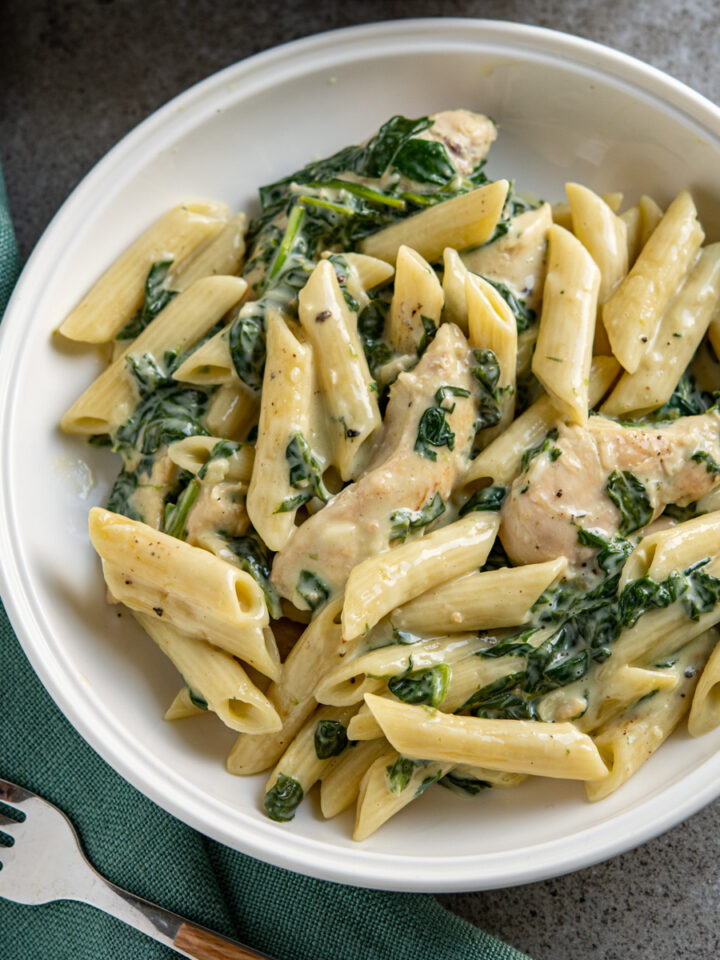 creamy garlic chicken spinach penne in a white bowl