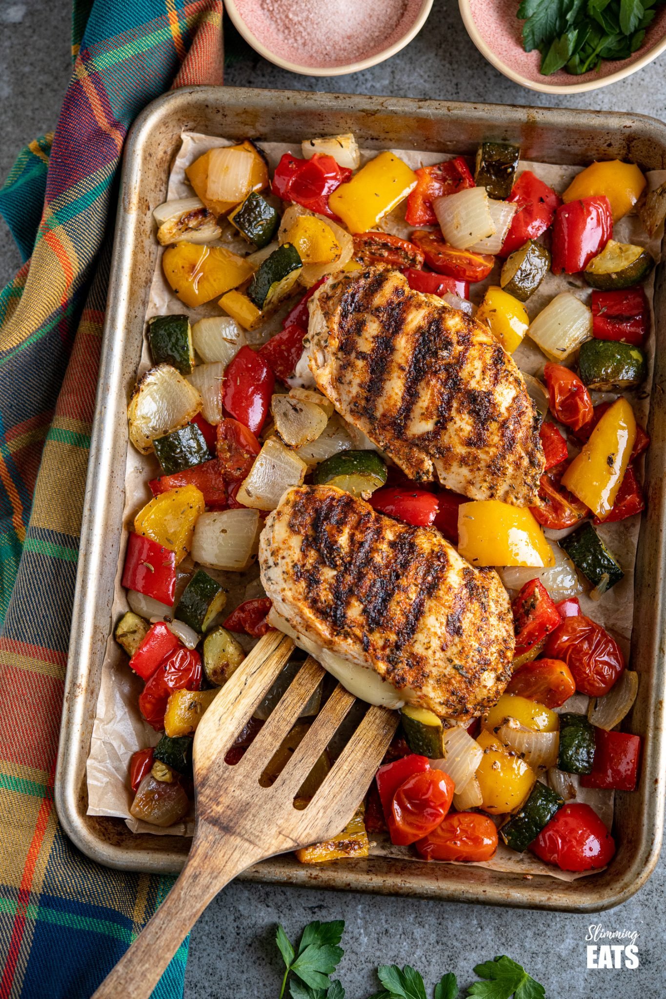 Simple seasoned Grilled Chicken Breast stuffed with mozzarella all delicious and melted served with a simple tray bake of roasted vegetables. #glutenfree #chicken #mozzarella #slimmingeats #weightwatchers #smartpoints #caloriecounting grilled chicken stuffed with mozzarella and roasted vegetables on a baking tray line with parchment paper