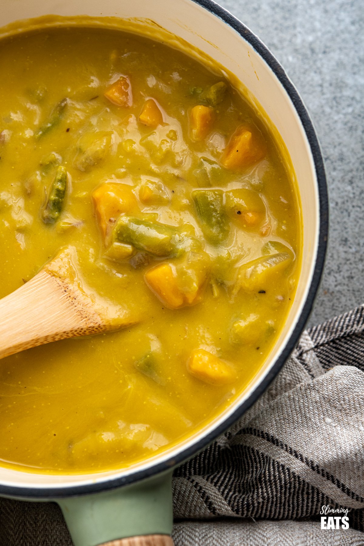 Asparagus and Sweet Potato Soup - delicious silky and creamy fresh asparagus soup with a subtle sweetness from cubes of sweet potato - pure comfort in a bowl. #glutenfree #dairyfree #slimmingworld #weightwatchers asparagus and sweet potato soup in pan with wooden handle