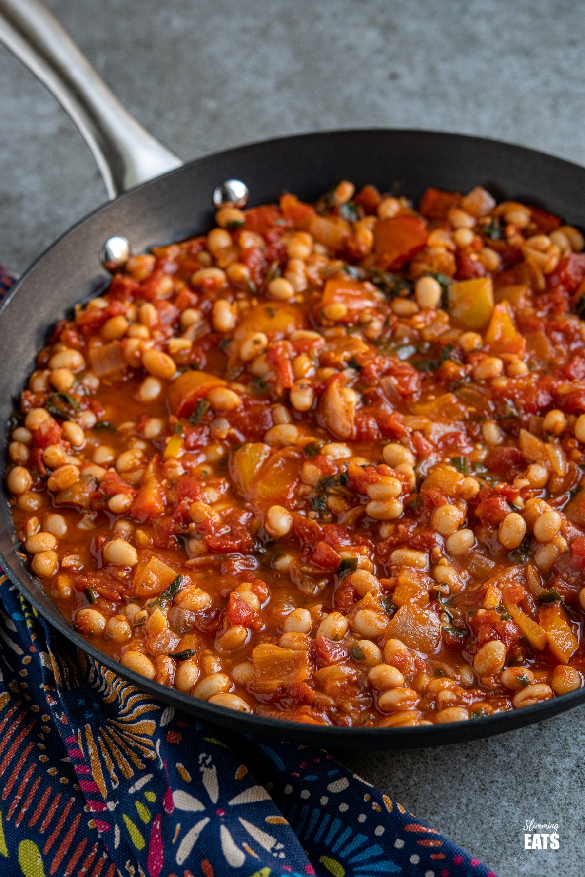 Mediterranean Tomatoes and White Beans - delicious rich tomatoes with peppers and white beans make this a perfect side or main. Tomatoes and White Beans in a black frying pan