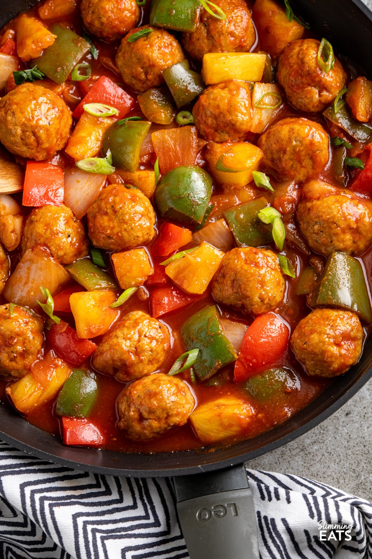 Sweet and Sour Chicken Meatballs - tender chicken meatballs in a delicious Chinese style Sweet and Sour sauce with peppers and onions. Gluten Free, Dairy Free, Slimming Eats and Weight Watchers friendly close up of sweet and sour chicken meatballs in black frying pan with vegetables and pineapple