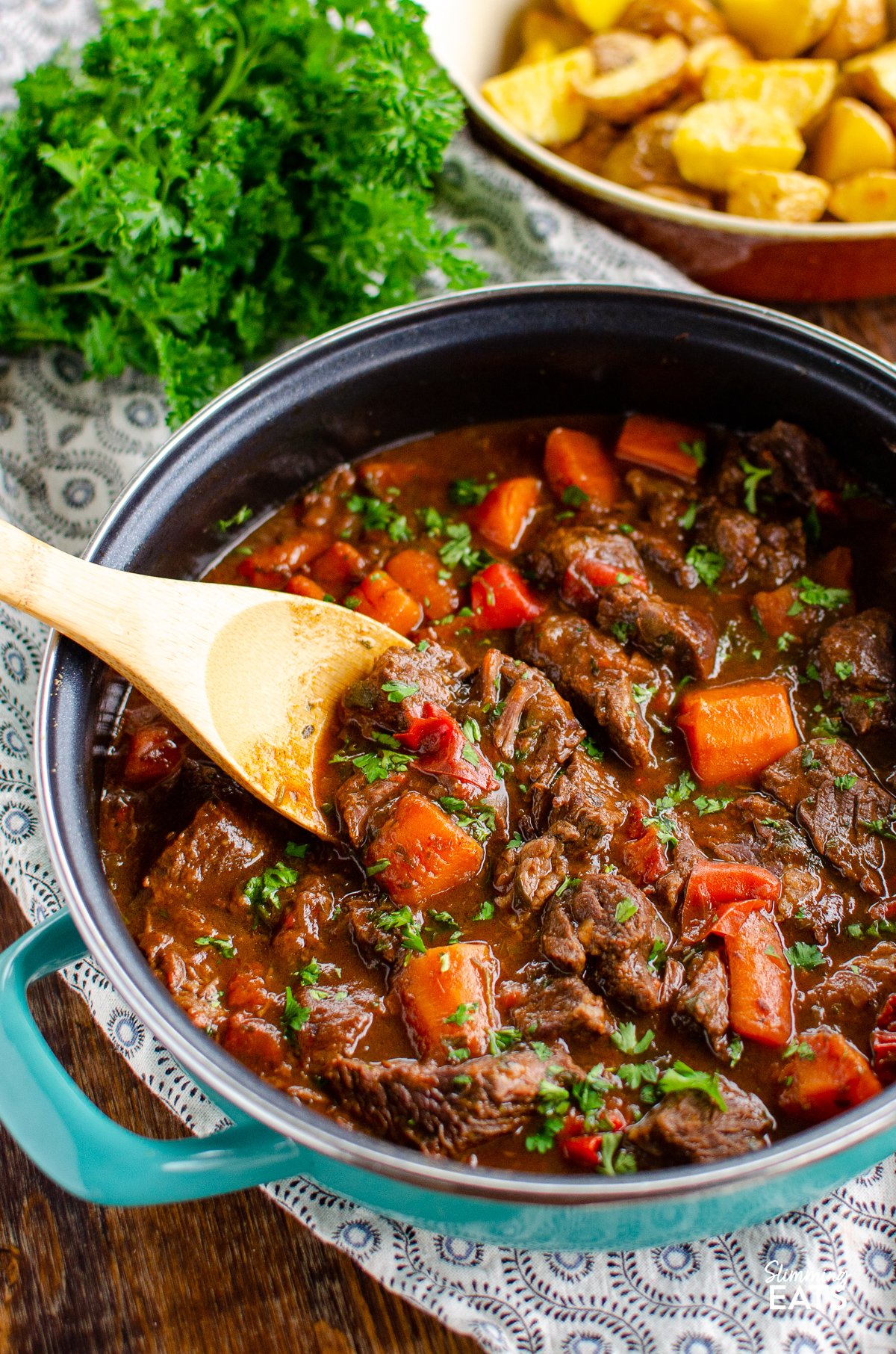 This delicious bowl of Balsamic Braised Beef is pure comfort food. Tender chunks of beef in a tangy rich tomato sauce. #glutenfree #dairyfree #instantpot #slowcooker #pressurecooker #paleo #slimmingworld #weightwatchers #beef balsamic braised beef in a casserole pan with wooden spoon