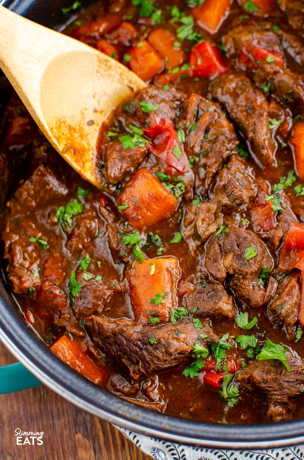 This delicious bowl of Balsamic Braised Beef is pure comfort food. Tender chunks of beef in a tangy rich tomato sauce. Gluten free, dairy free, Slimming World and Weight Watchers friendly close up of balsamic braised beef with wooden spoon