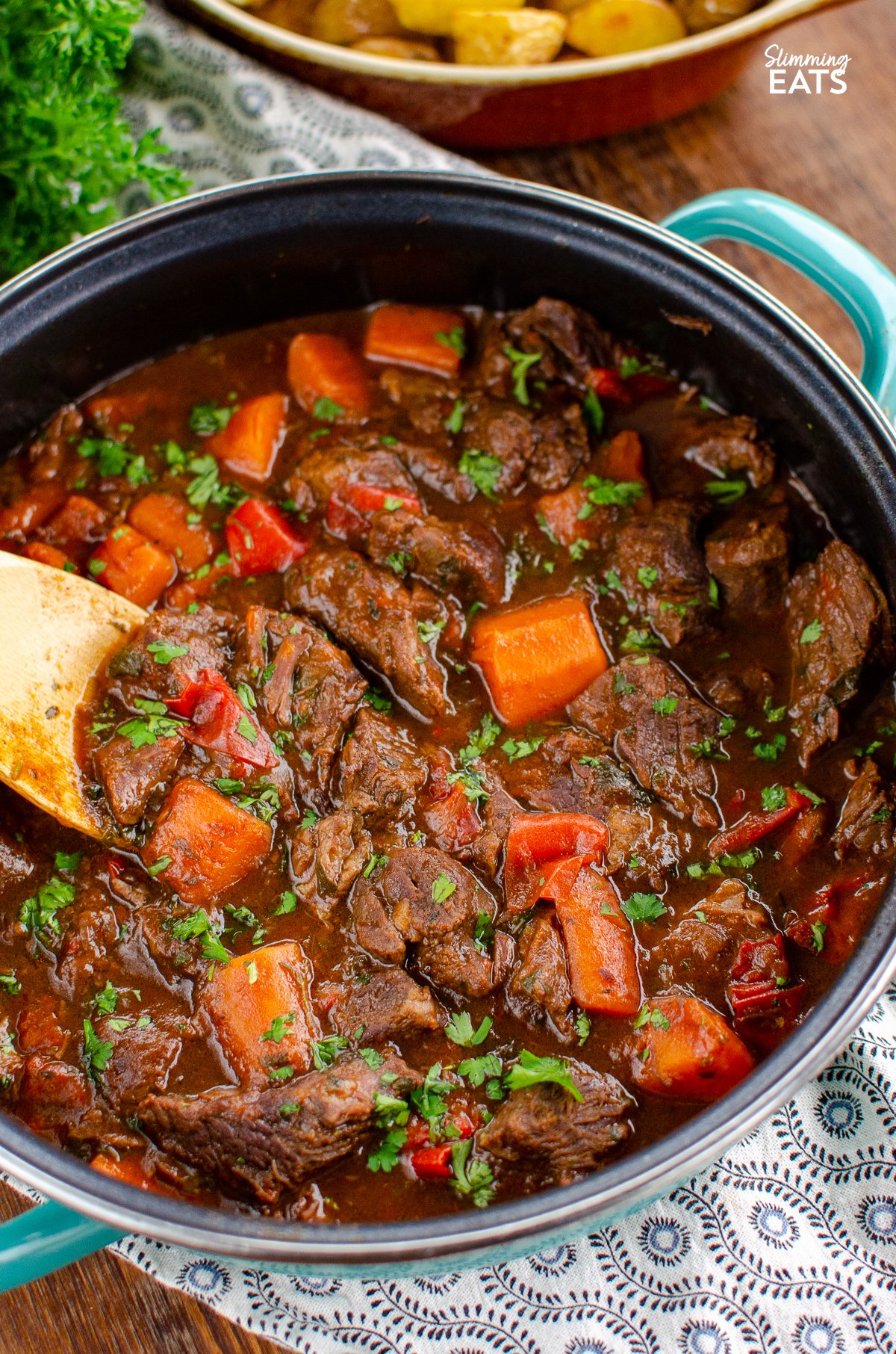 close up of balsamic braised beef in casserole dish with wooden spoon.