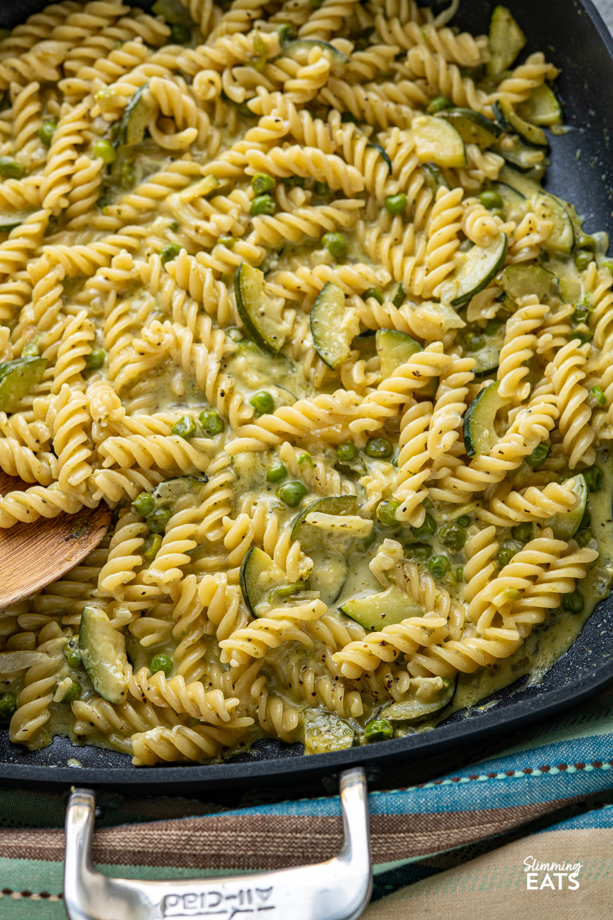 close up of One Pot Creamy Pesto Courgette Pea Pasta in black all-clad skillet with two handles 