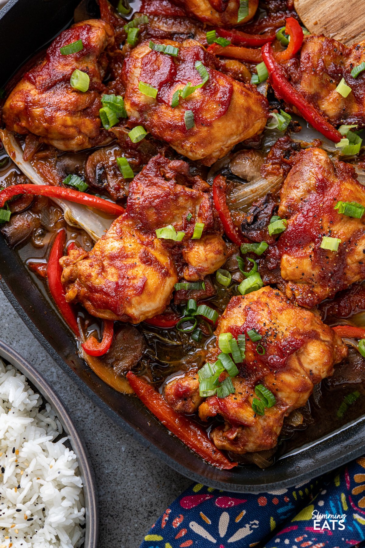 Sriracha Peach Chicken Bake - delicious tender chicken thighs with a spicy sriracha peach marinade baked over a bed of mixed vegetables. Gluten free, dairy free, Slimming Eats and Watchers friendly close up of Sriracha Peach Chicken Bake in black square skillet