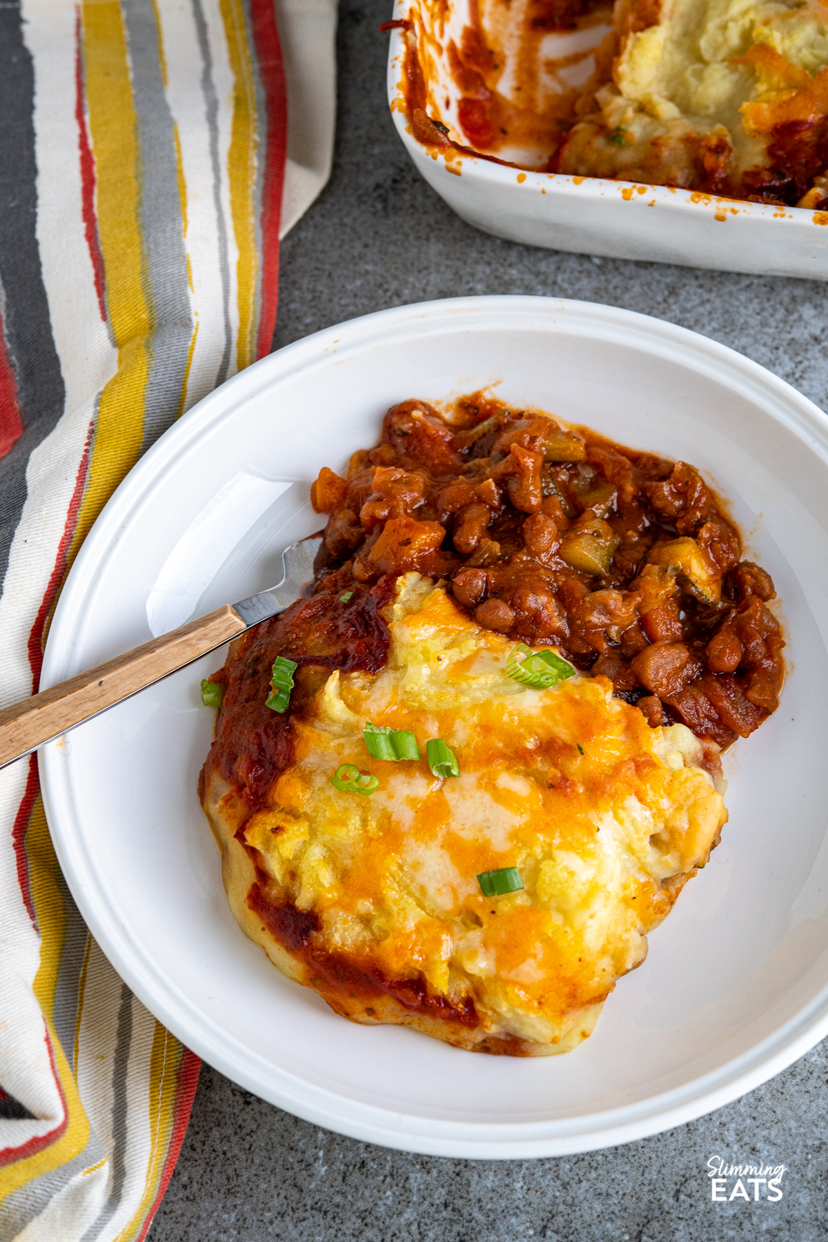serving of Baked Bean Cheesy Potato Topped Pie in white bowl with fork