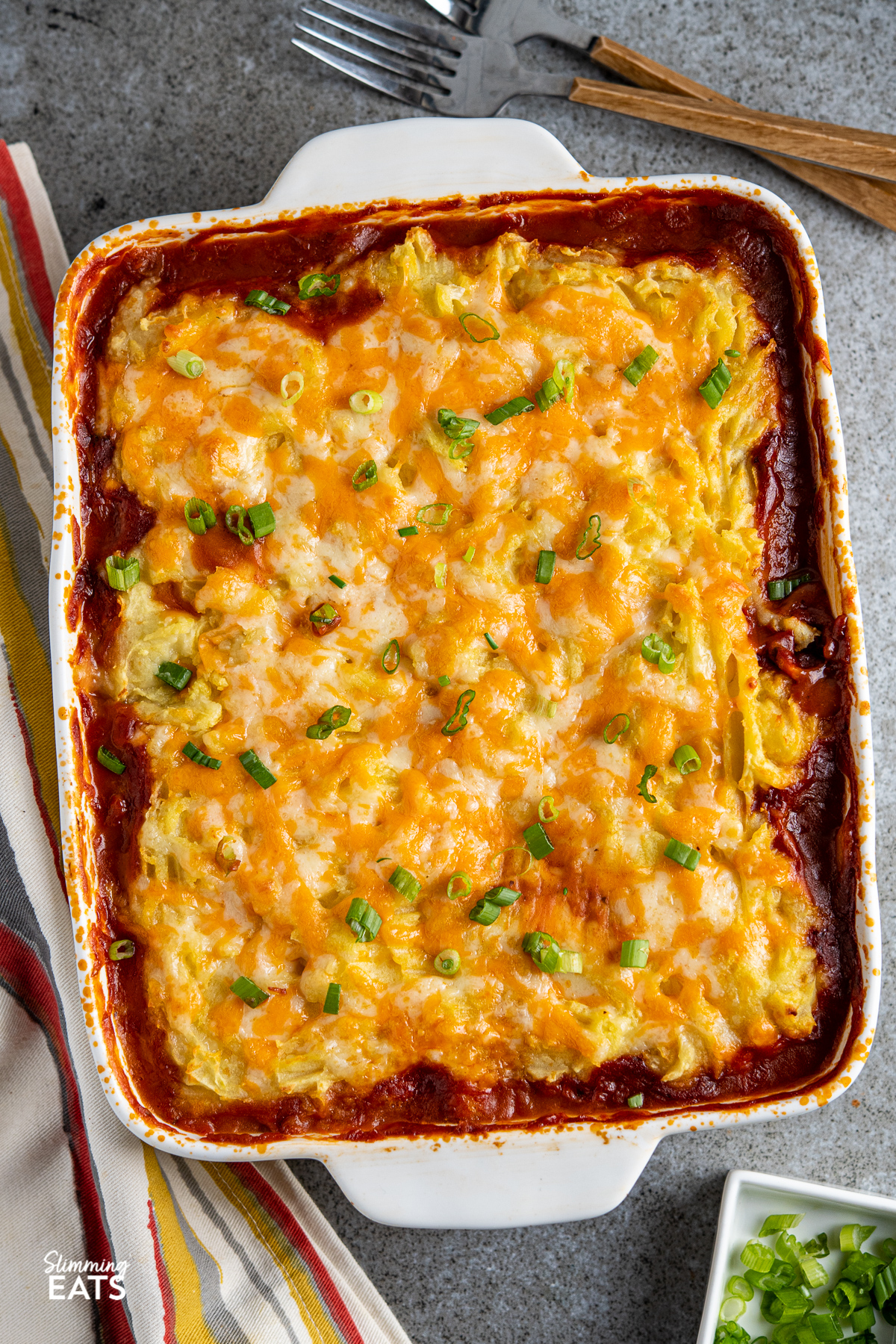 Baked Bean Cheesy Potato Topped Pie  in white baking dish with scattered sliced spring onions