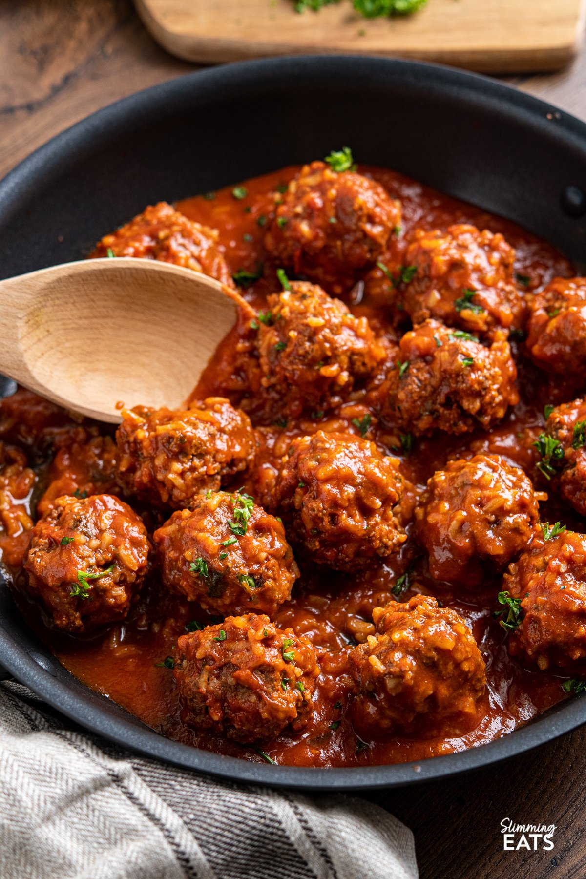 Porcupine Meatballs - Tender beef meatballs with rice in a rich and delicious tomato sauce - A perfect recipe for the whole family. Slimming Eats and Weight Watchers friendly Porcupine Meatballs with wooden spoon in black skillet