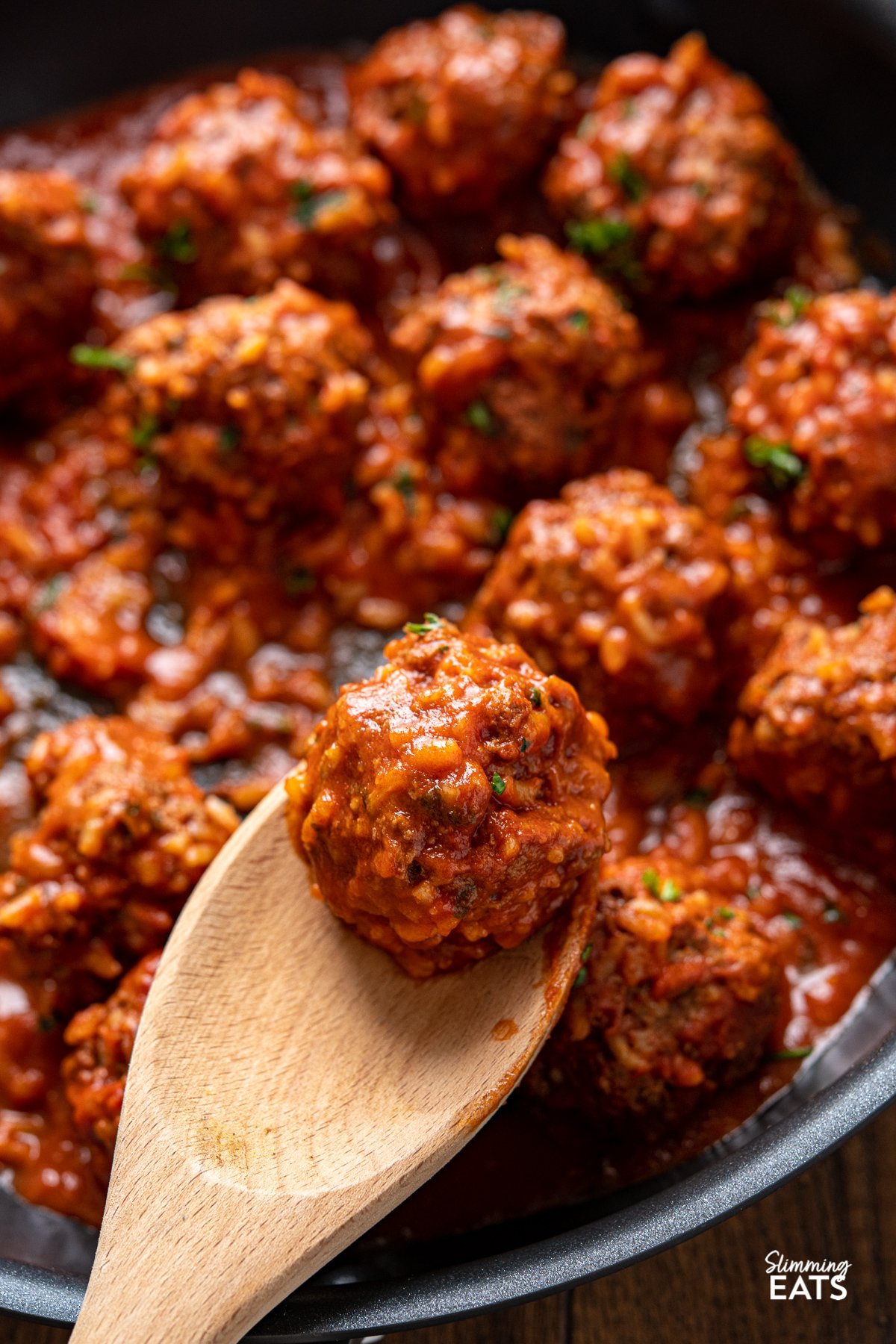Porcupine Meatballs - Tender beef meatballs with rice in a rich and delicious tomato sauce - A perfect recipe for the whole family. Slimming Eats and Weight Watchers friendly close up of Porcupine Meatballs on wooden spoon in black skillet