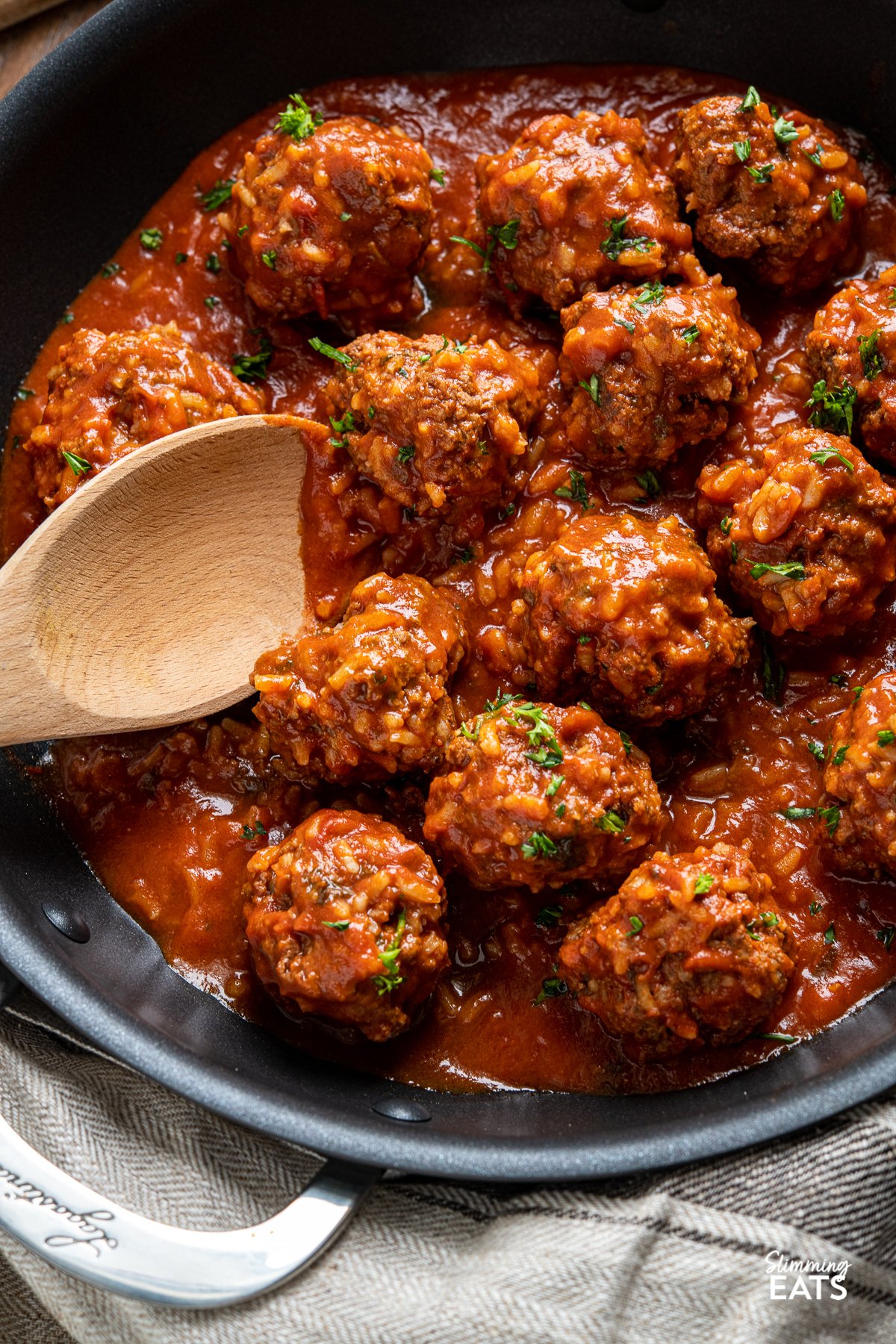 Porcupine Meatballs - Tender beef meatballs with rice in a rich and delicious tomato sauce - A perfect recipe for the whole family. Slimming Eats and Weight Watchers friendly Porcupine Meatballs with wooden spoon in black skillet