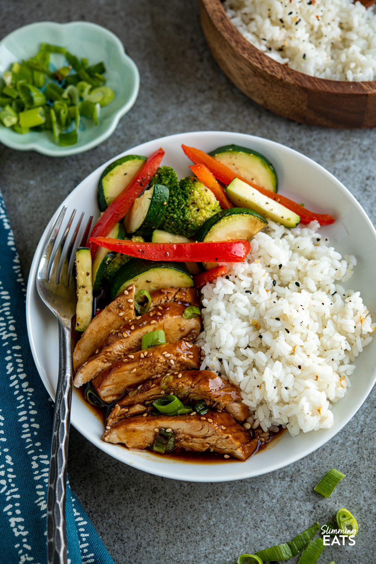 sliced Slow Cooker Teriyaki Chicken on white plate with rice and stir fried red pepper, zucchini and broccoli