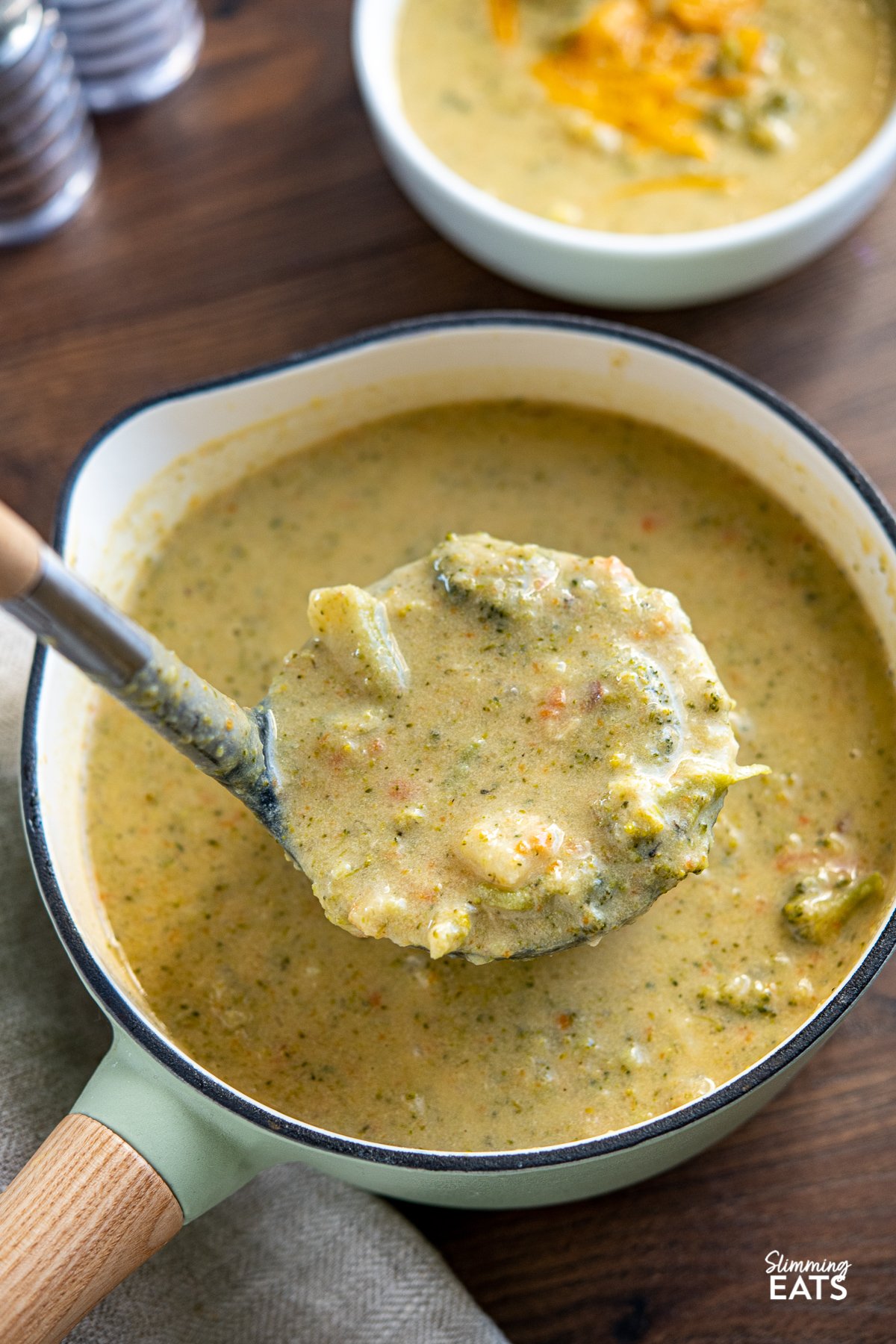 Lighter Broccoli Cheddar Soup being ladled from cast iron saucepan