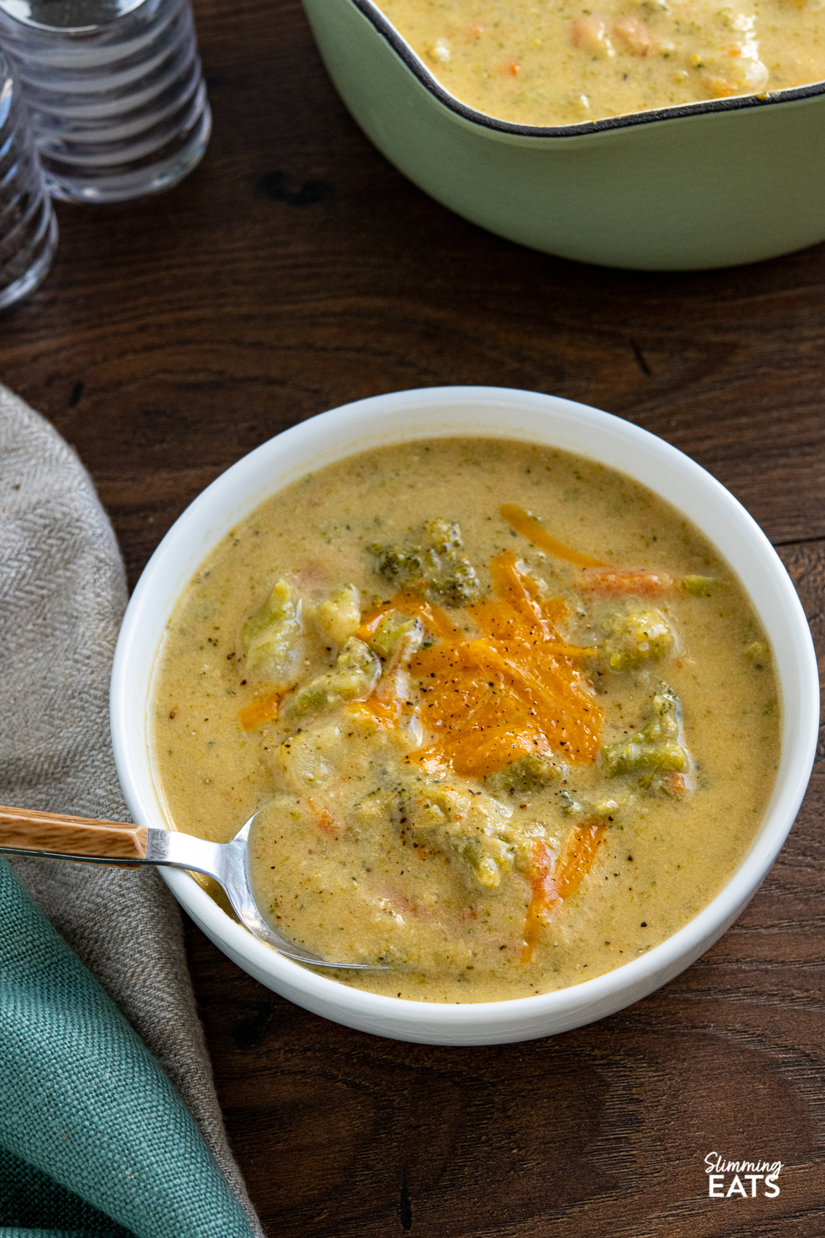 Lighter Broccoli Cheddar Soup in a white bowl with grated cheddar