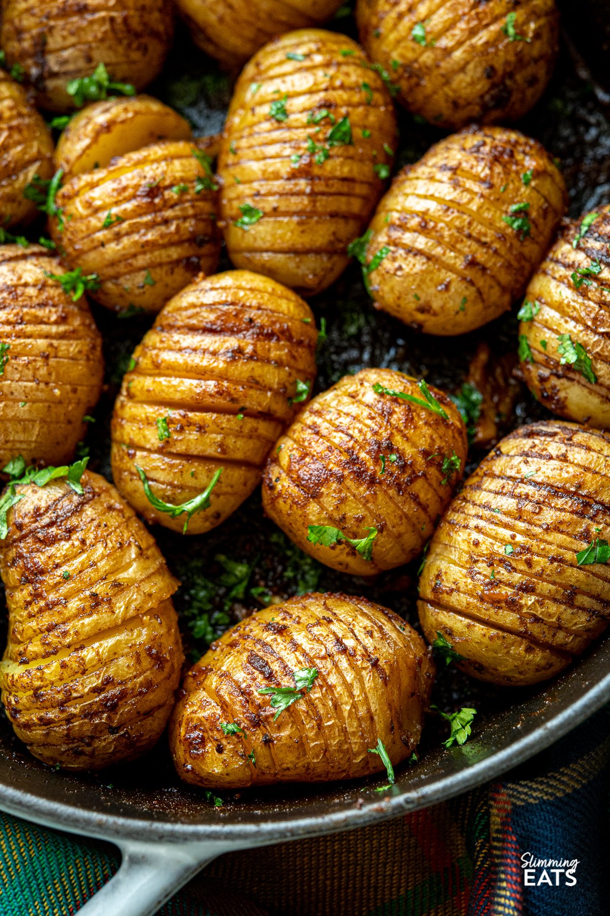 Garlic Hasselback Potatoes are one of the best kind of baked potato you will ever make, the buttery garlic melts perfectly into all the thin slices in the potato adding heaps of flavour. Vegetarian, Slimming Eats and Weight Watchers friendly close up Garlic Hasselback Potatoes in a grey staub cast iron pan