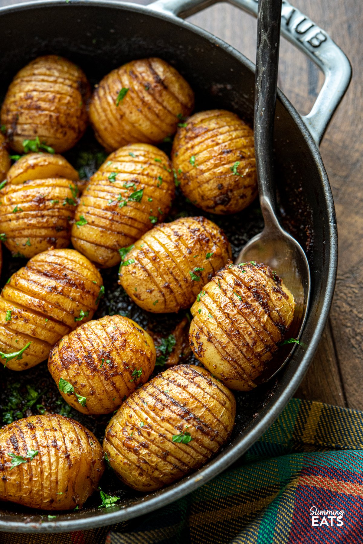Garlic Hasselback Potatoes are one of the best kind of baked potato you will ever make, the buttery garlic melts perfectly into all the thin slices in the potato adding heaps of flavour. Vegetarian, Slimming Eats and Weight Watchers friendly close up Garlic Hasselback Potatoes in a grey staub cast iron pan