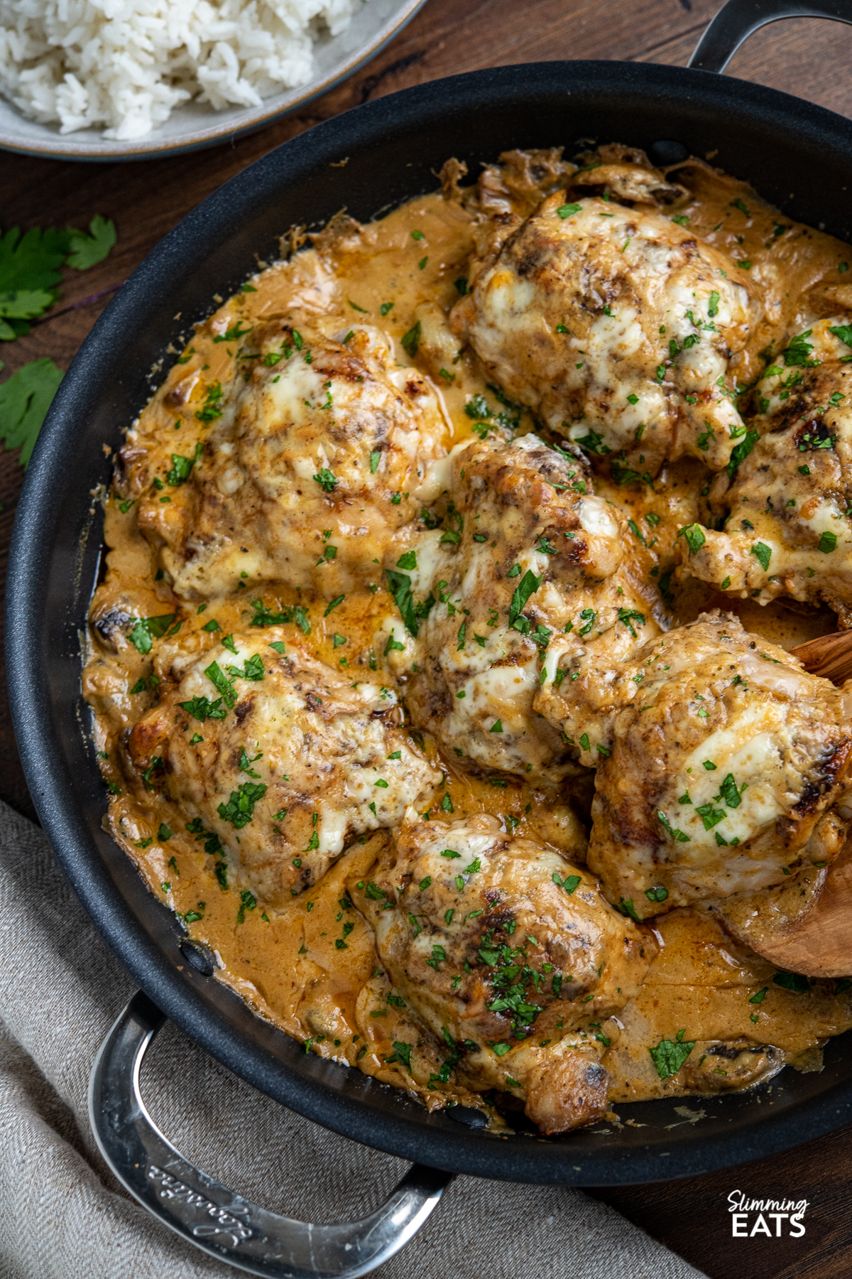 close up of smothered creamy garlic chicken with mushrooms in black double handled frying pan 