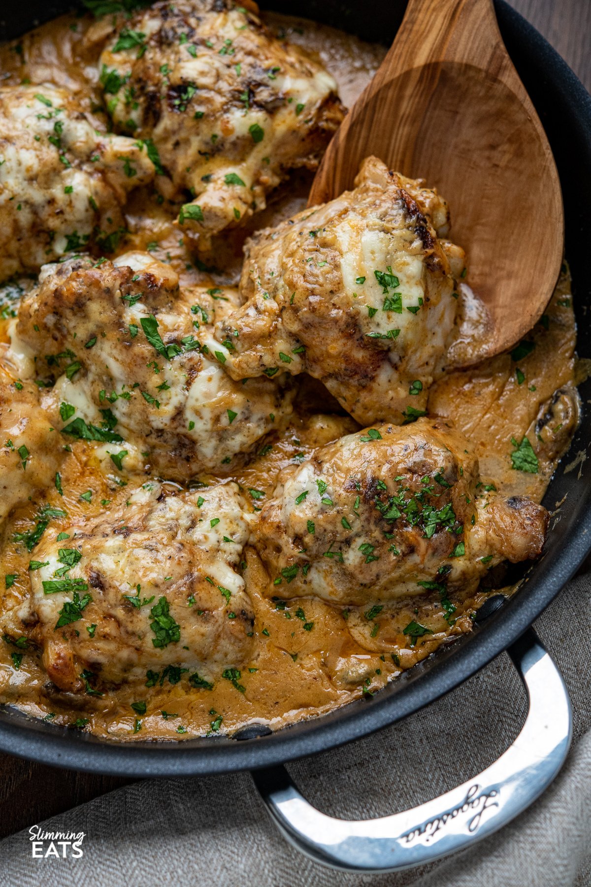 close up of smothered creamy garlic chicken with mushrooms in black double handled frying pan 