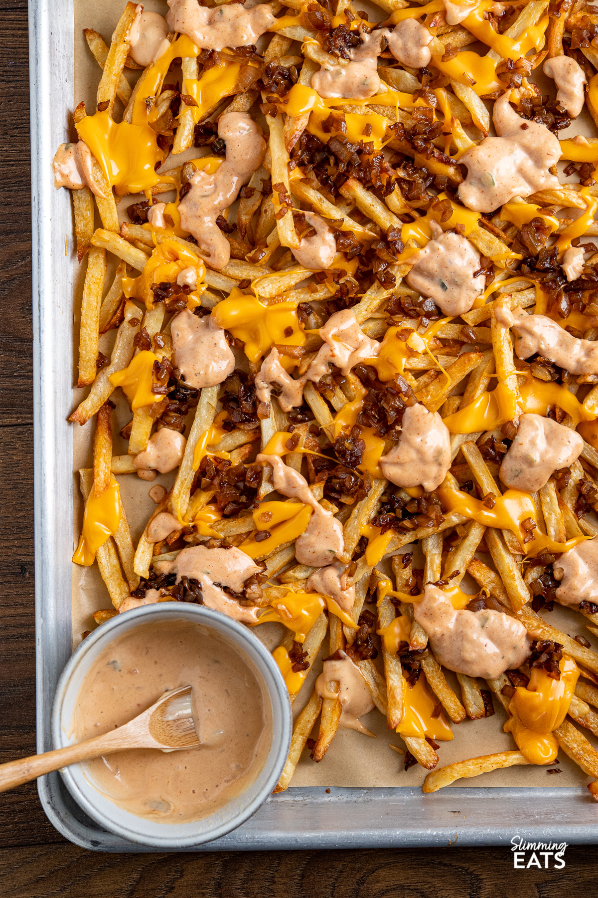 Copycat Oven Baked Animal Style Fries on a baking tray with a bowl of special sauce