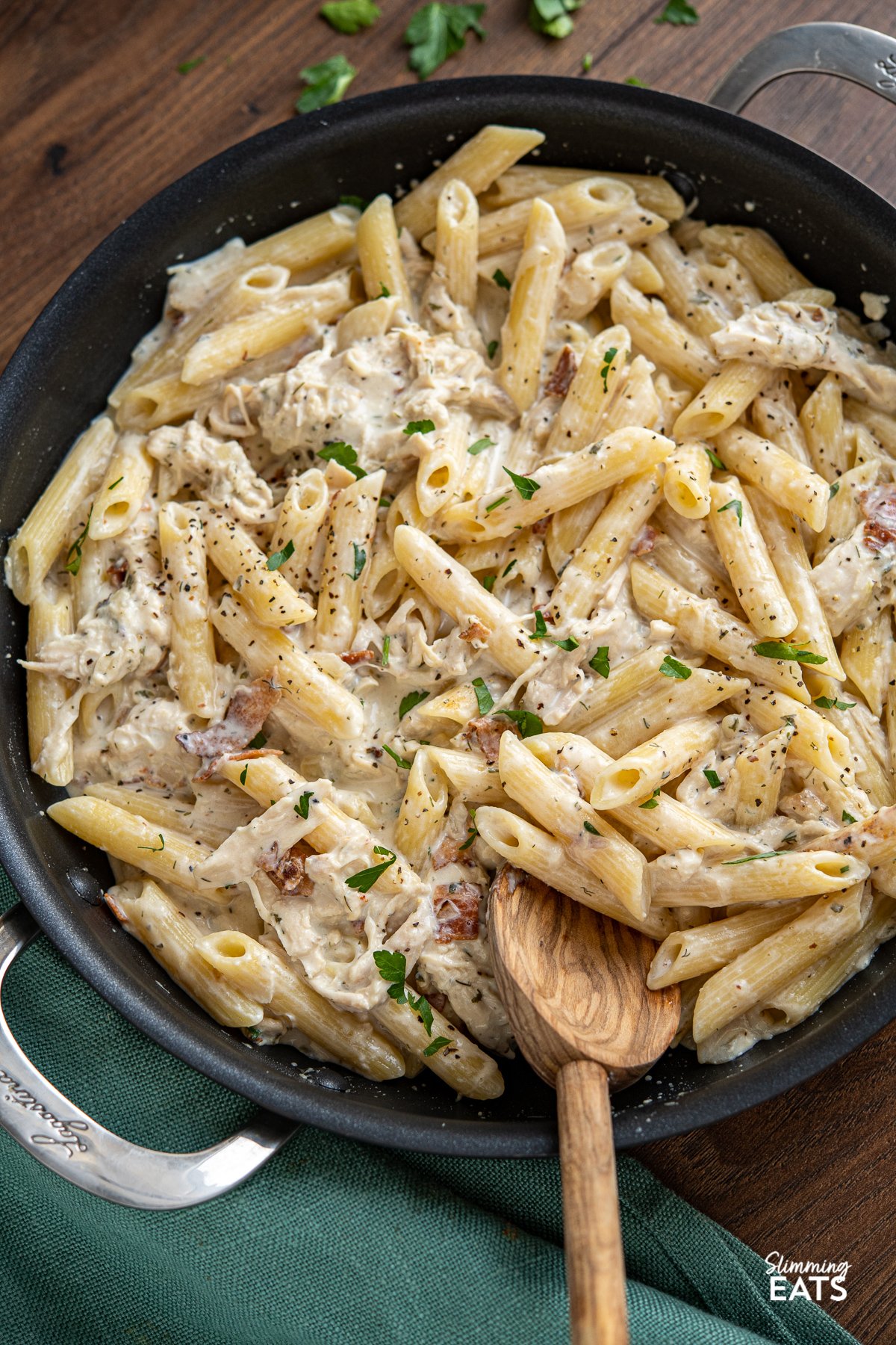 A pasta dish with the perfect combination - chicken and penne pasta in a creamy ranch flavoured pasta sauce all finished off with some smoky crispy bacon. What's not to love? What's not to love? Slimming Eats, Weight Watchers and Calorie Counting friendly recipes creamy chicken bacon ranch pasta in black frying pan with wooden spoon