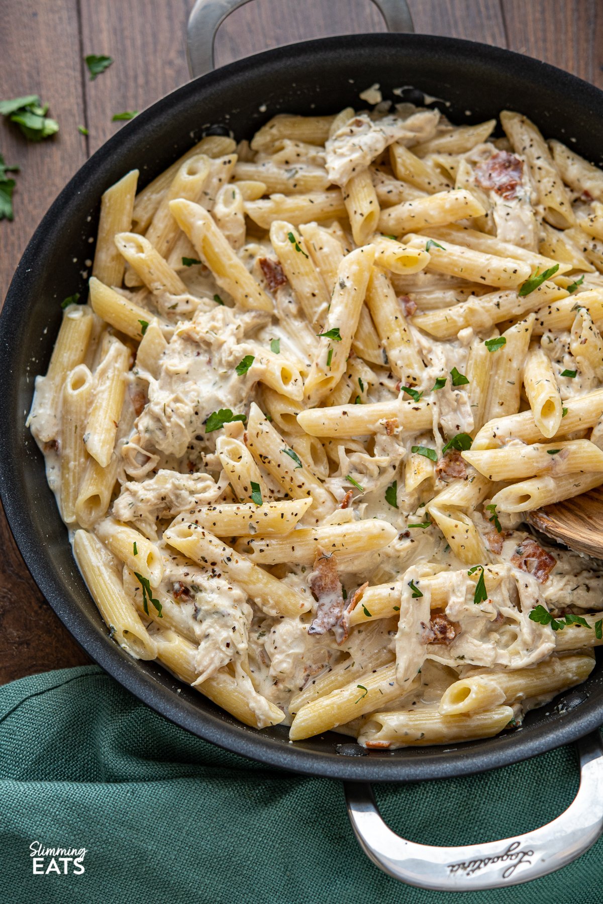A pasta dish with the perfect combination - chicken and penne pasta in a creamy ranch flavoured pasta sauce all finished off with some smoky crispy bacon. What's not to love? What's not to love? Slimming Eats, Weight Watchers and Calorie Counting friendly recipes creamy chicken bacon ranch pasta in black frying pan with wooden spoon