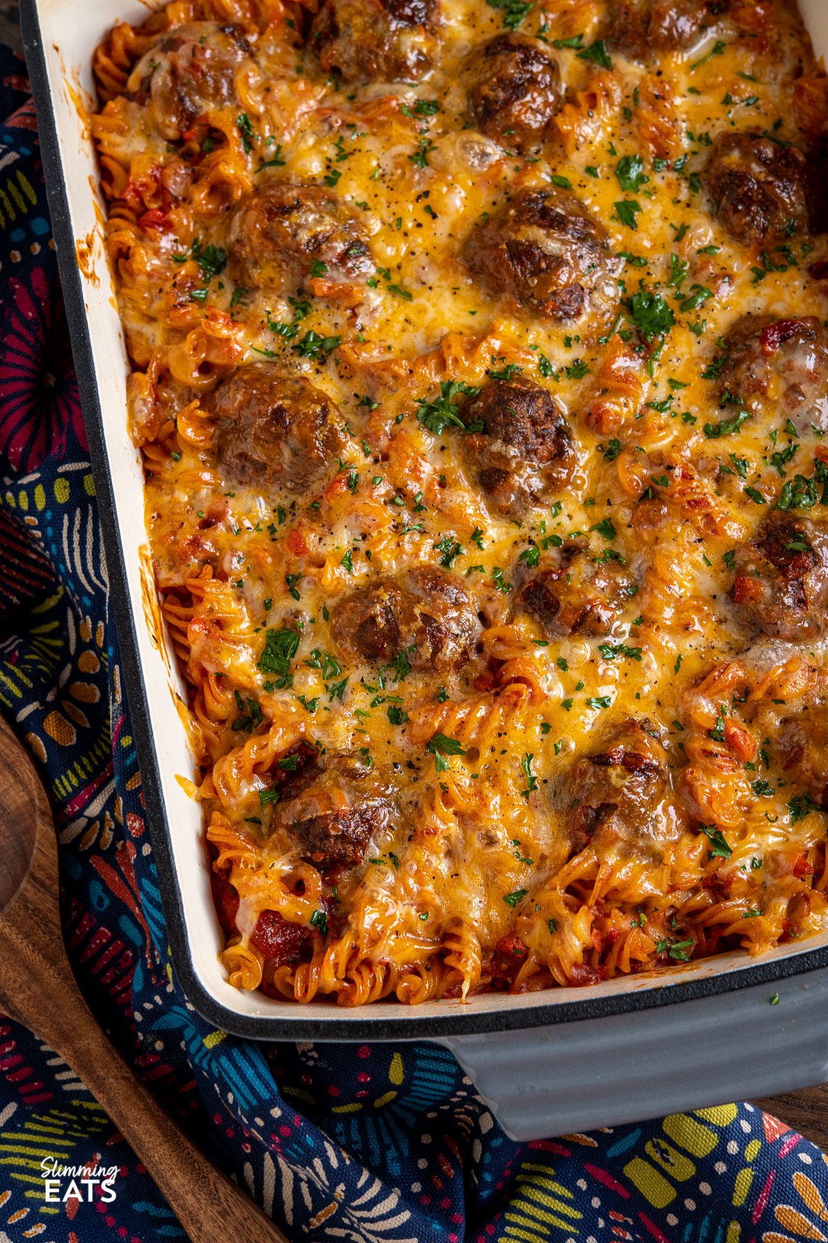 Cheesy Meatball Pasta Bake - delicious and lean homemade beef meatballs in a rich tomato sauce all stirred into fusilli pasta, topped with cheese and baked in the oven until melted and golden for a perfect family meal. Cheesy Meatball Pasta Bake in baking dish