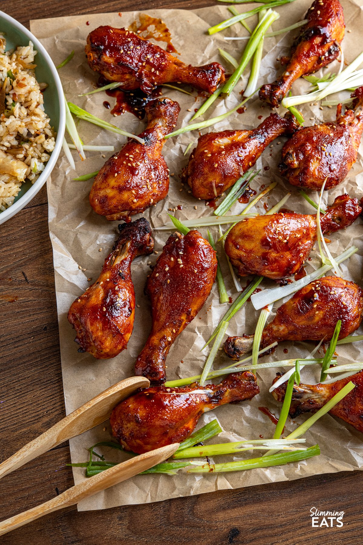 Korean Gochujang Chicken Drumsticks on a parchment lined baking sheet with scattered slices of green onion