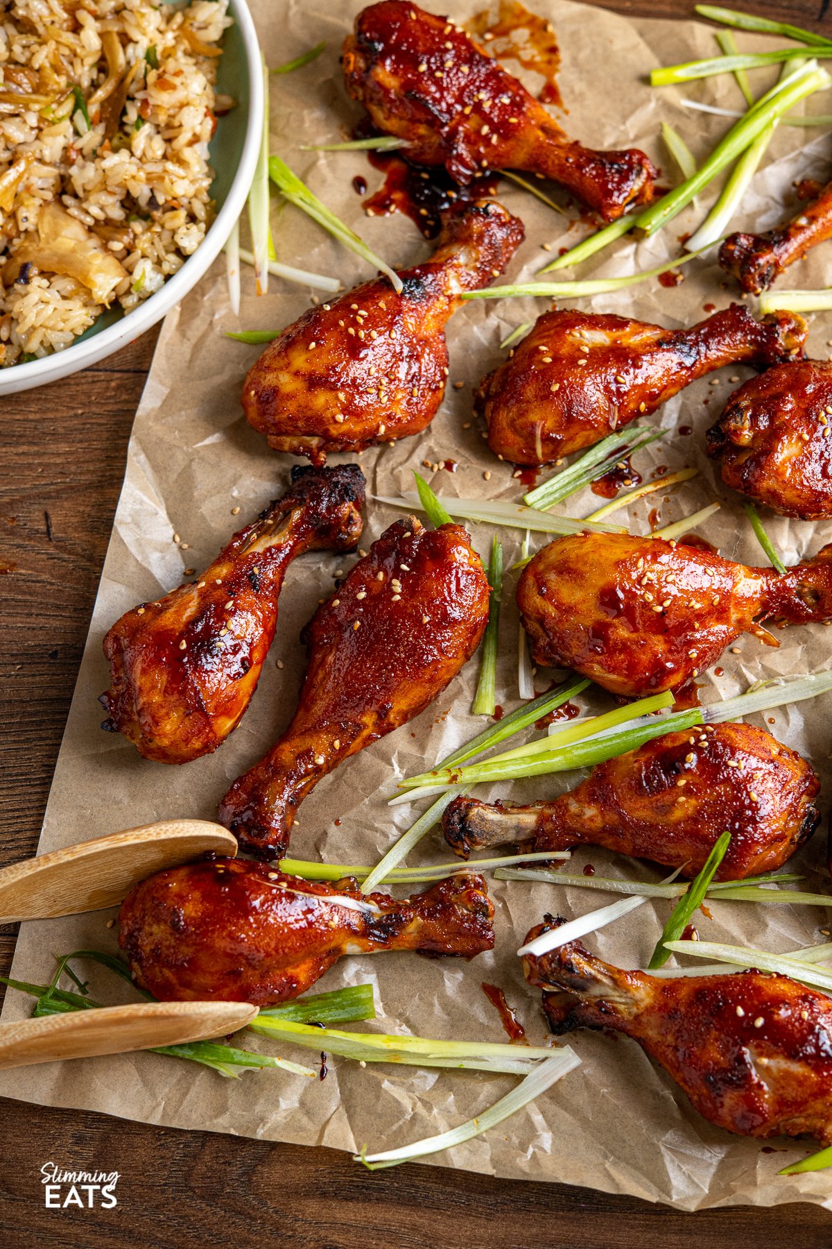 Korean Gochujang Chicken Drumsticks - tender oven baked chicken drumsticks coated in a delicious Korean Gochujang marinade. Korean Gochujang Chicken Drumsticks on a parchment lined baking sheet with scattered slices of green onion