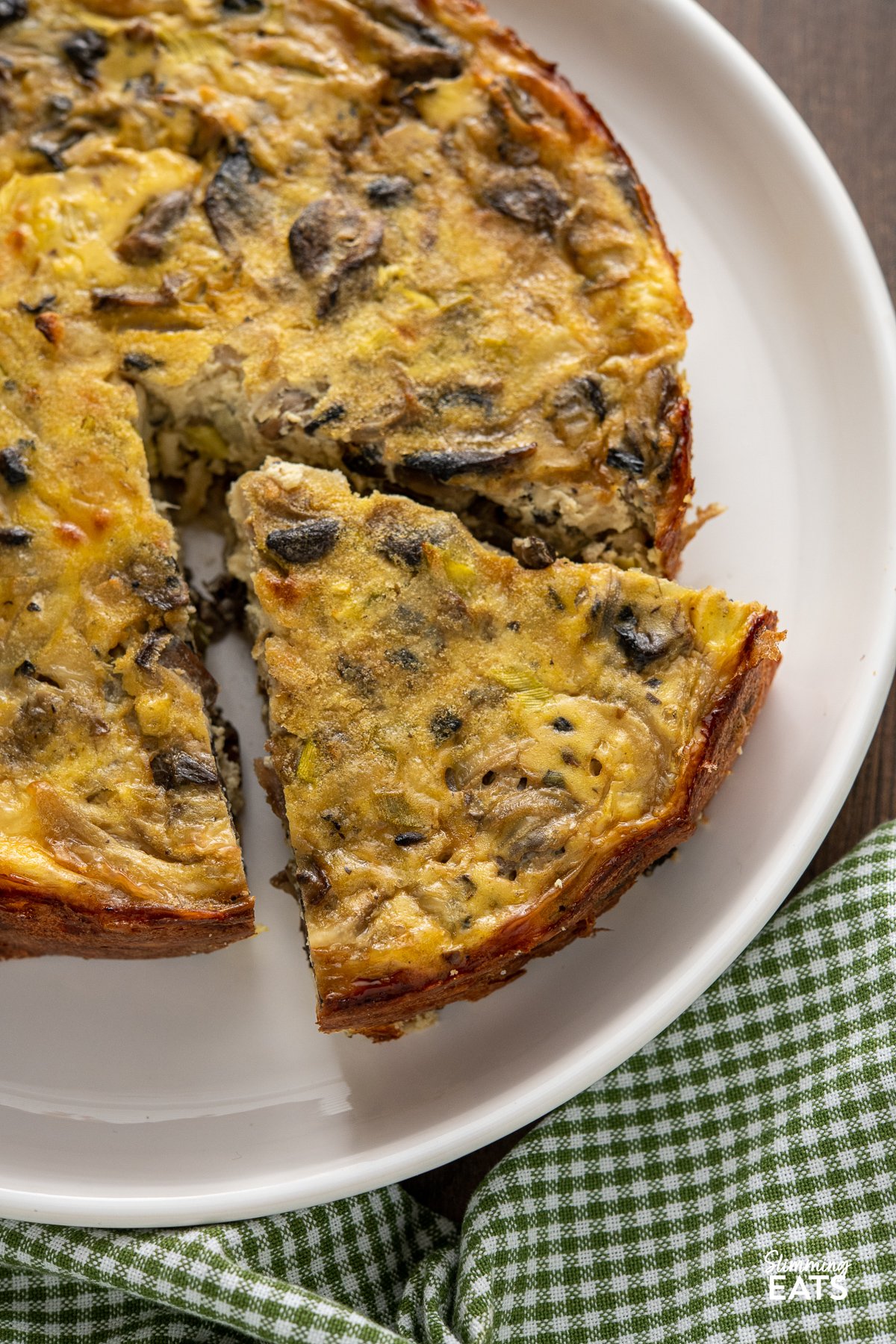 close up of sliced crustless mushroom quiche on white plate