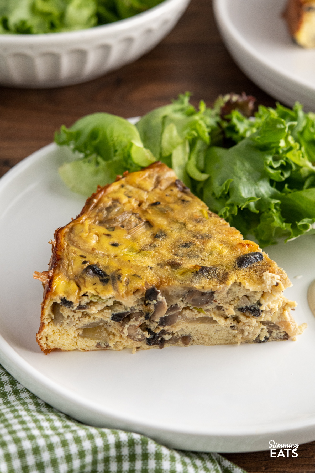 close up of slice of crustless mushroom quiche on white plate