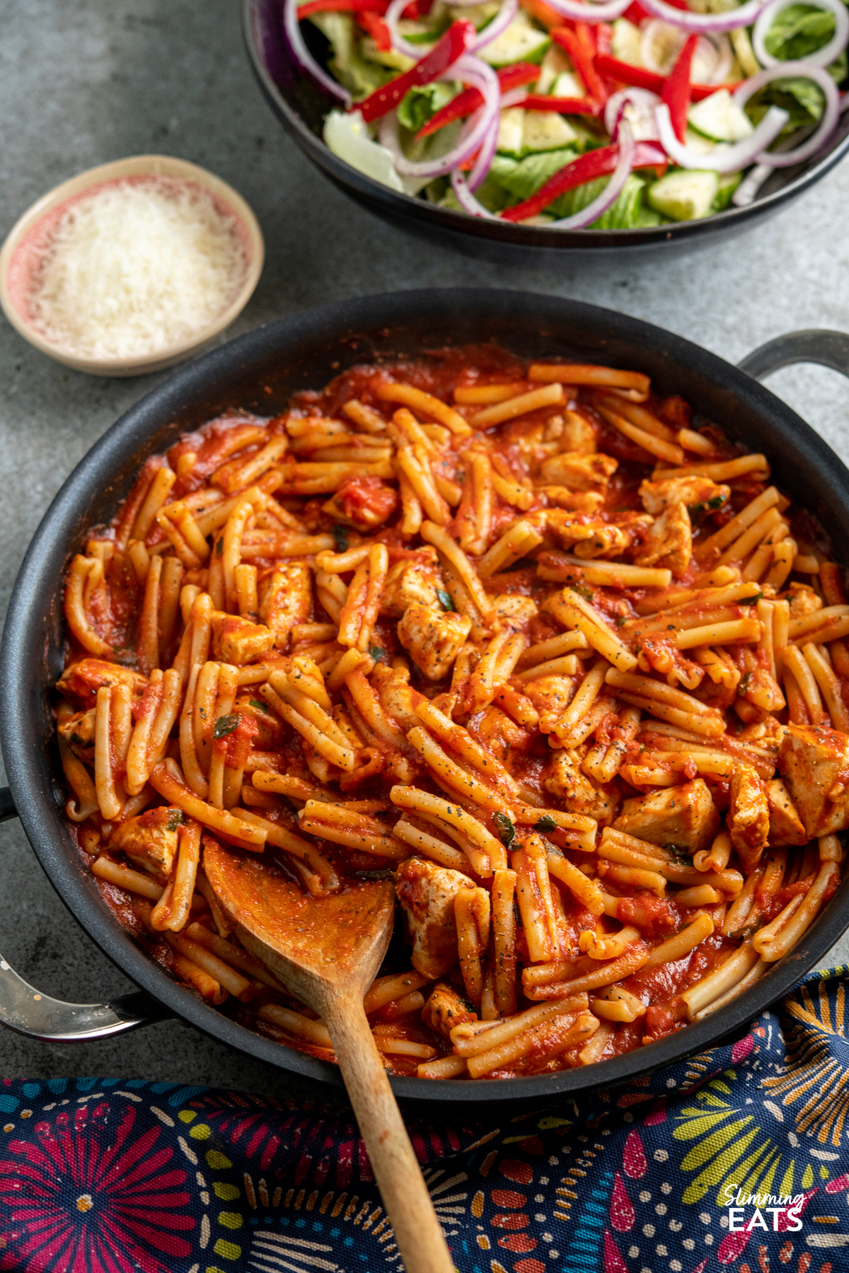 Chicken Arrabbiata Pasta in frying pan with bowl of salad