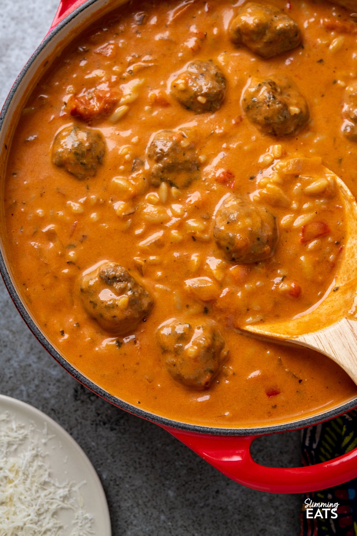 Flavoursome silky creamy tomato soup with orzo pasta and herby garlic chicken meatballs makes this a complete meal in a bowl that the whole family will love. close up of Creamy Tomato Orzo Soup with Chicken Meatballs in a cerise le creuset casserole pot.