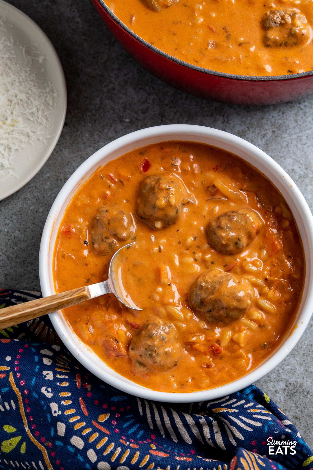 Creamy Tomato Orzo Soup with Chicken Meatballs in a white bowl with spoon